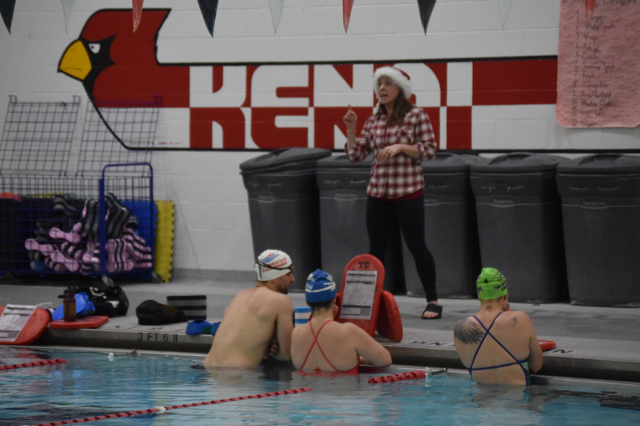 Angie Brennan directs swimmers as they prepare for a workout set during a Top of the World Swimming practice on Wednesday, Dec. 14, 2022, at Kenai Central High School in Kenai, Alaska. (Jake Dye/Peninsula Clarion)