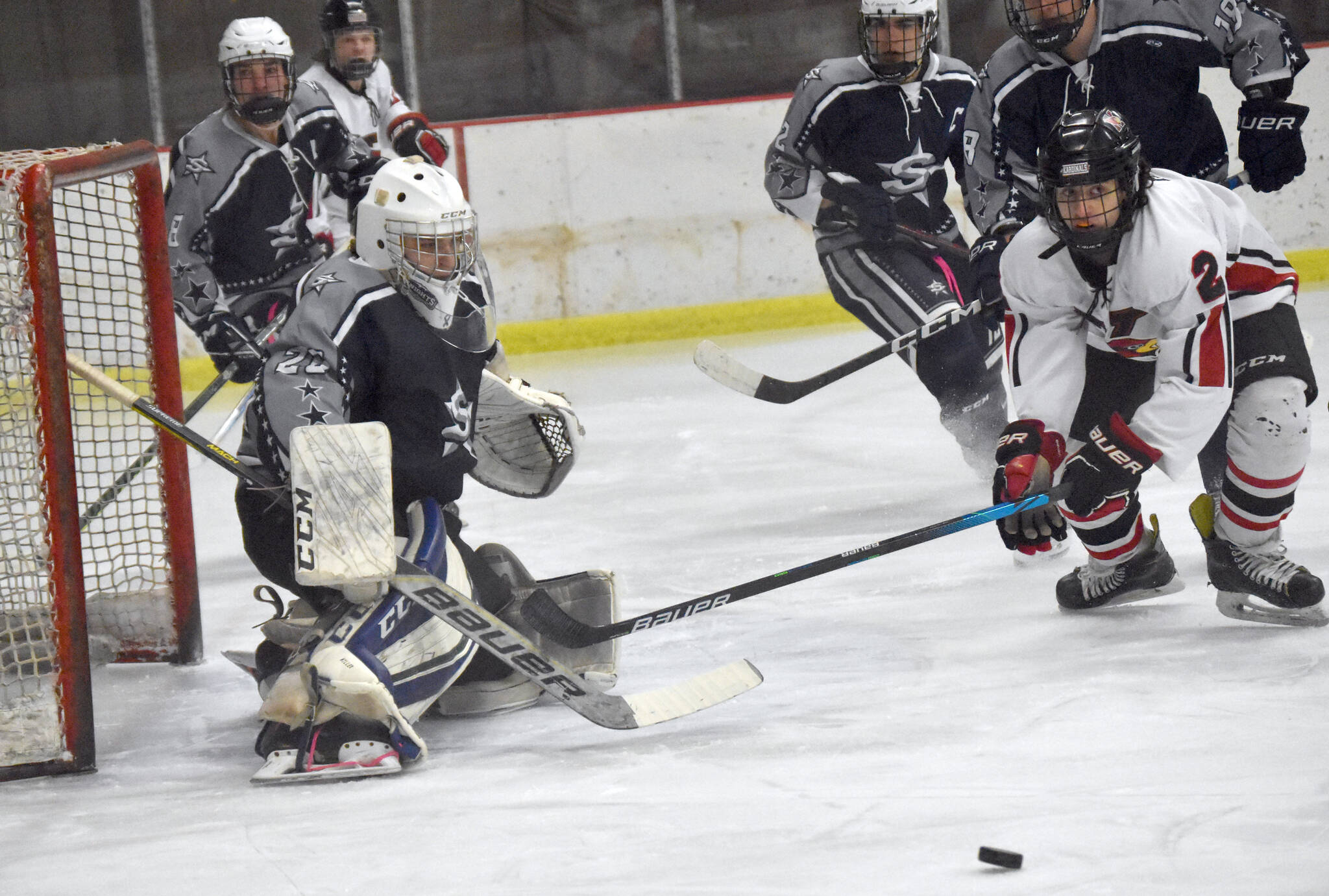 Soldotna goalie Jackson Purcell steers the puck wide of the net and Kenai Central’s Logan Mese on Thursday, Dec. 15, 2022, at the Kenai Multi-Purpose Facility in Kenai, Alaska. (Photo by Jeff Helminiak/Peninsula Clarion)