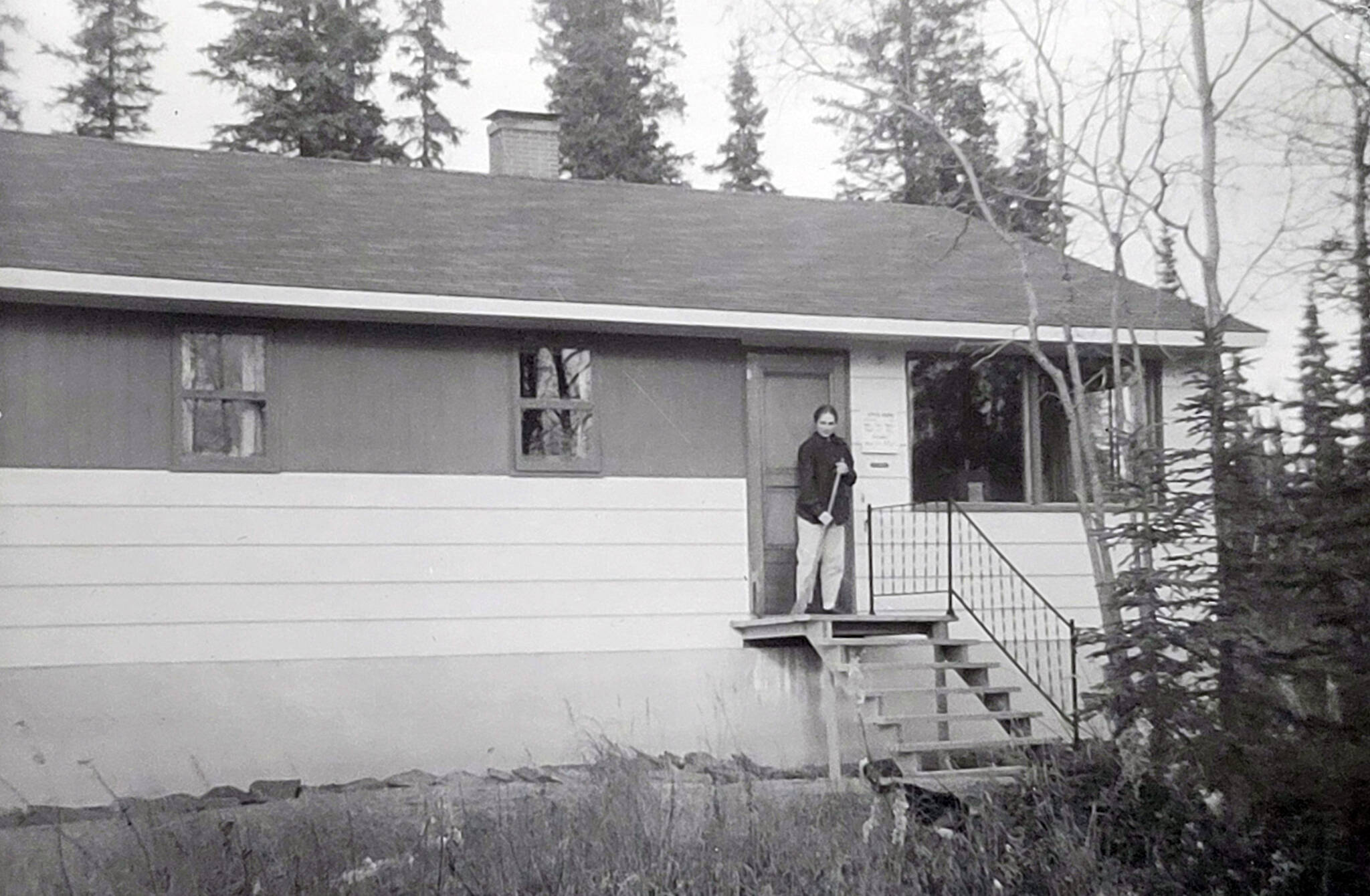 Dr. Marian Goble sweeps her clinic porch on McCollum Drive, circa 1959-60. (Photo courtesy of Ben and Marian Goble)