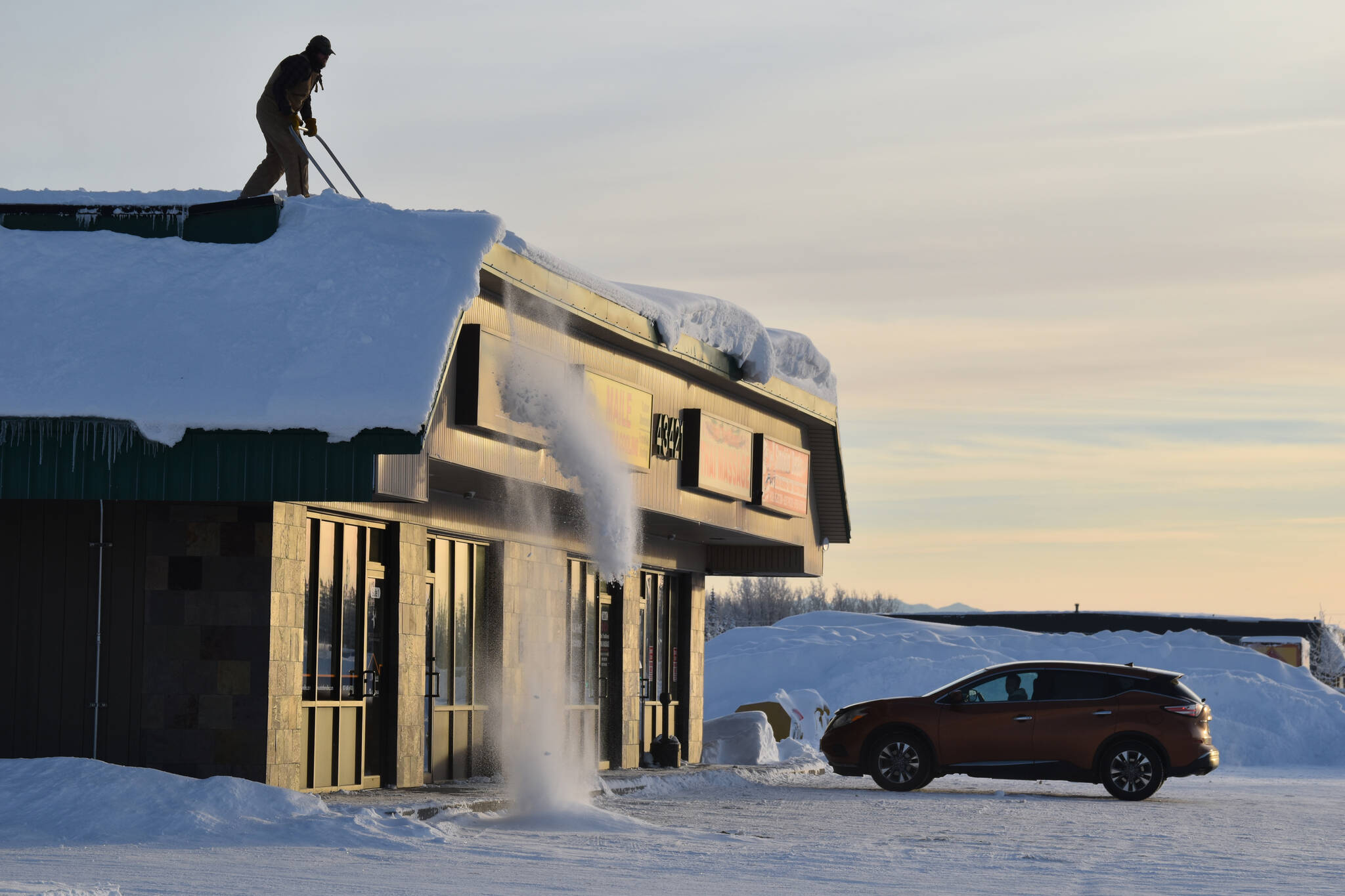 Snow is cleared from a roof near the Copper Center Soldotna, Alaska, on Friday, Dec. 16, 2022. Several nearby businesses were closed after a roof collapse. (Jake Dye/Peninsula Clarion)
