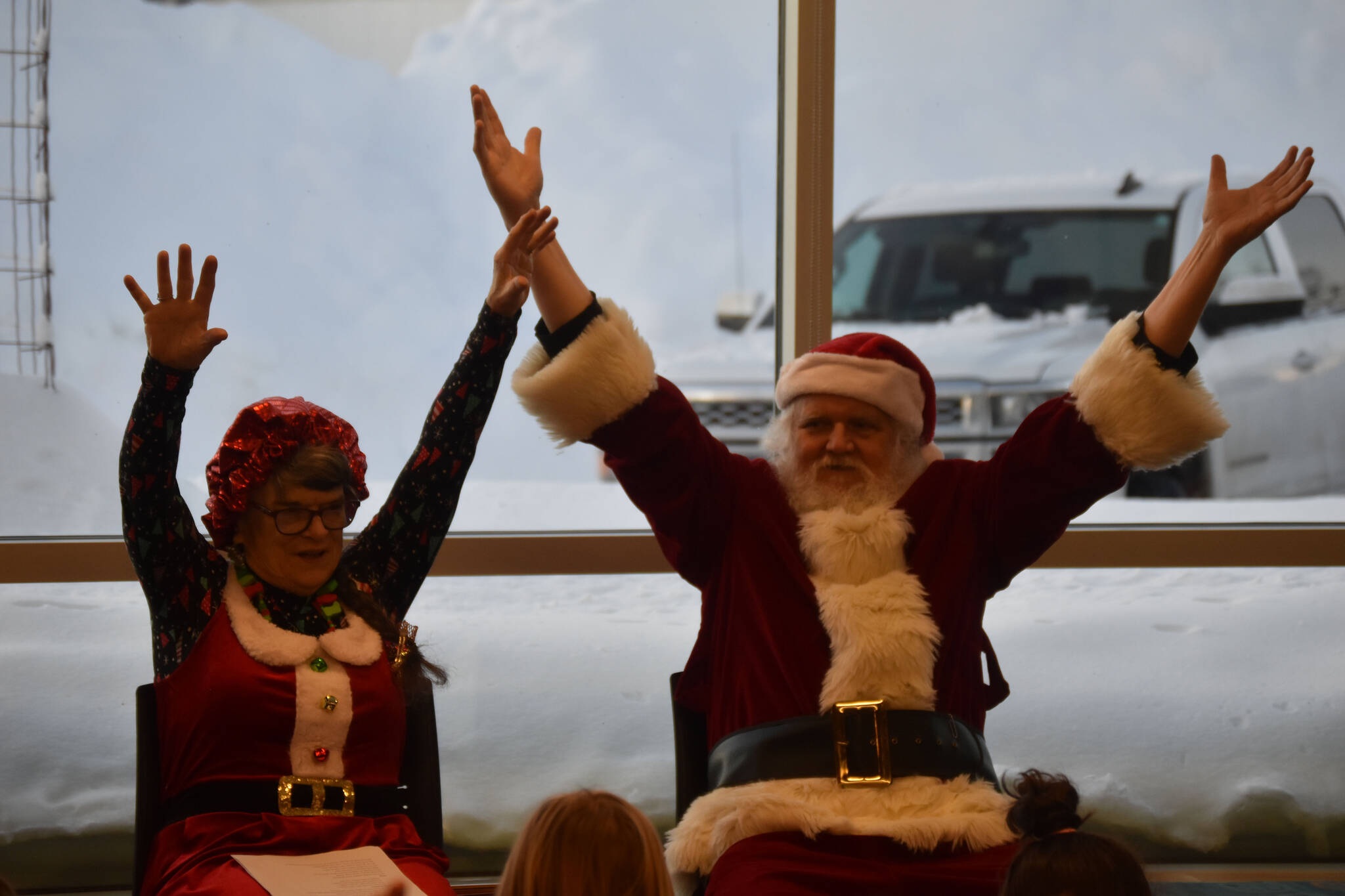 Mrs. Claus (Kit Hill) and Santa (Ken Aaron) raise their arms as they participate in a song during Story Time with Mrs. Claus at the Kenai Community Library in Kenai, Alaska, on Monday, Dec. 19, 2022. (Jake Dye/Peninsula Clarion)