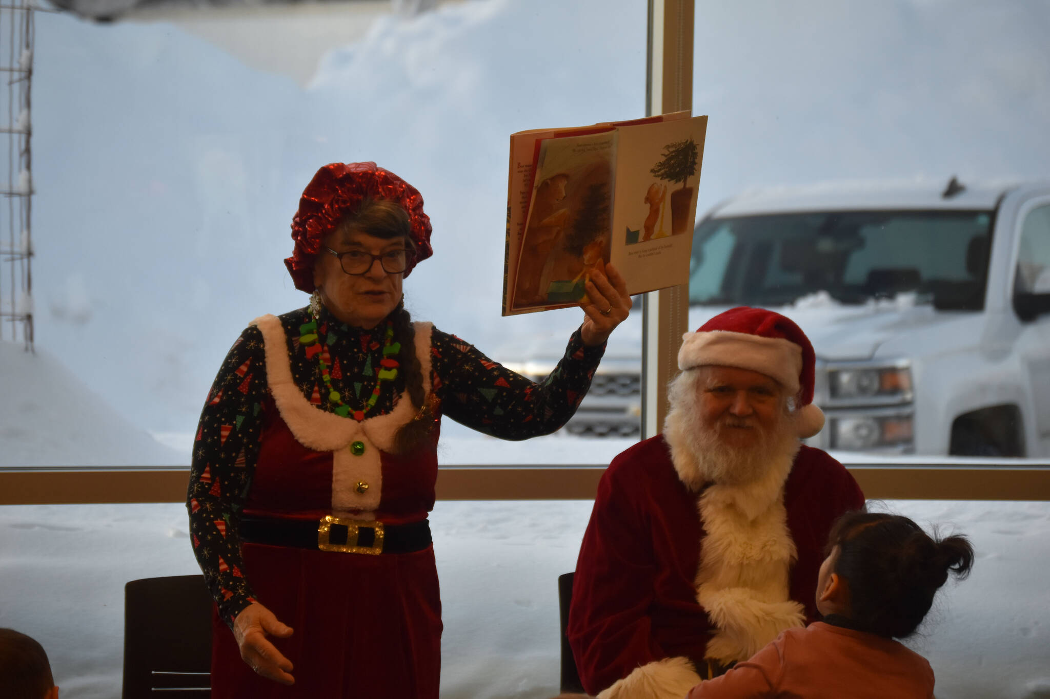 Mrs. Claus, played by Kit Hill, shows the pictures in her storybook to the kids during Story Time with Mrs. Claus at the Kenai Community Library in Kenai, Alaska, on Monday, Dec. 19, 2022. (Jake Dye/Peninsula Clarion)