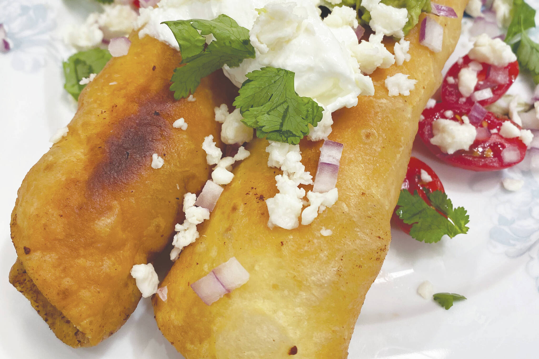 Adobo Chicken Floutas are topped with queso, sour cream, cilantro, onions and tomatoes. (Photo by Tressa Dale/Peninsula Clarion)