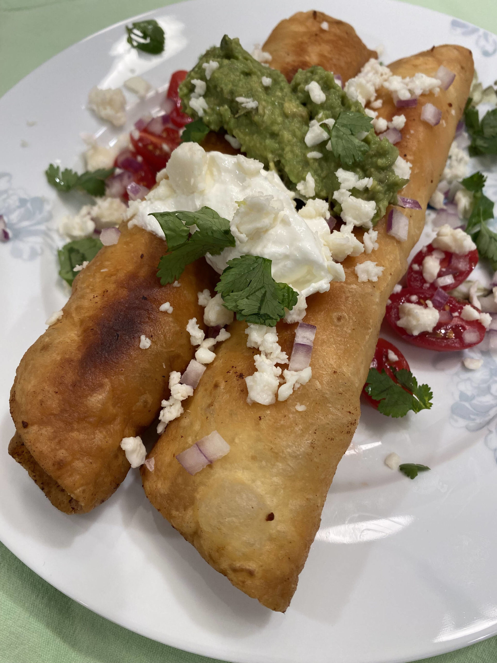 Adobo Chicken Floutas are topped with queso, sour cream, cilantro, onions and tomatoes. (Photo by Tressa Dale/Peninsula Clarion)