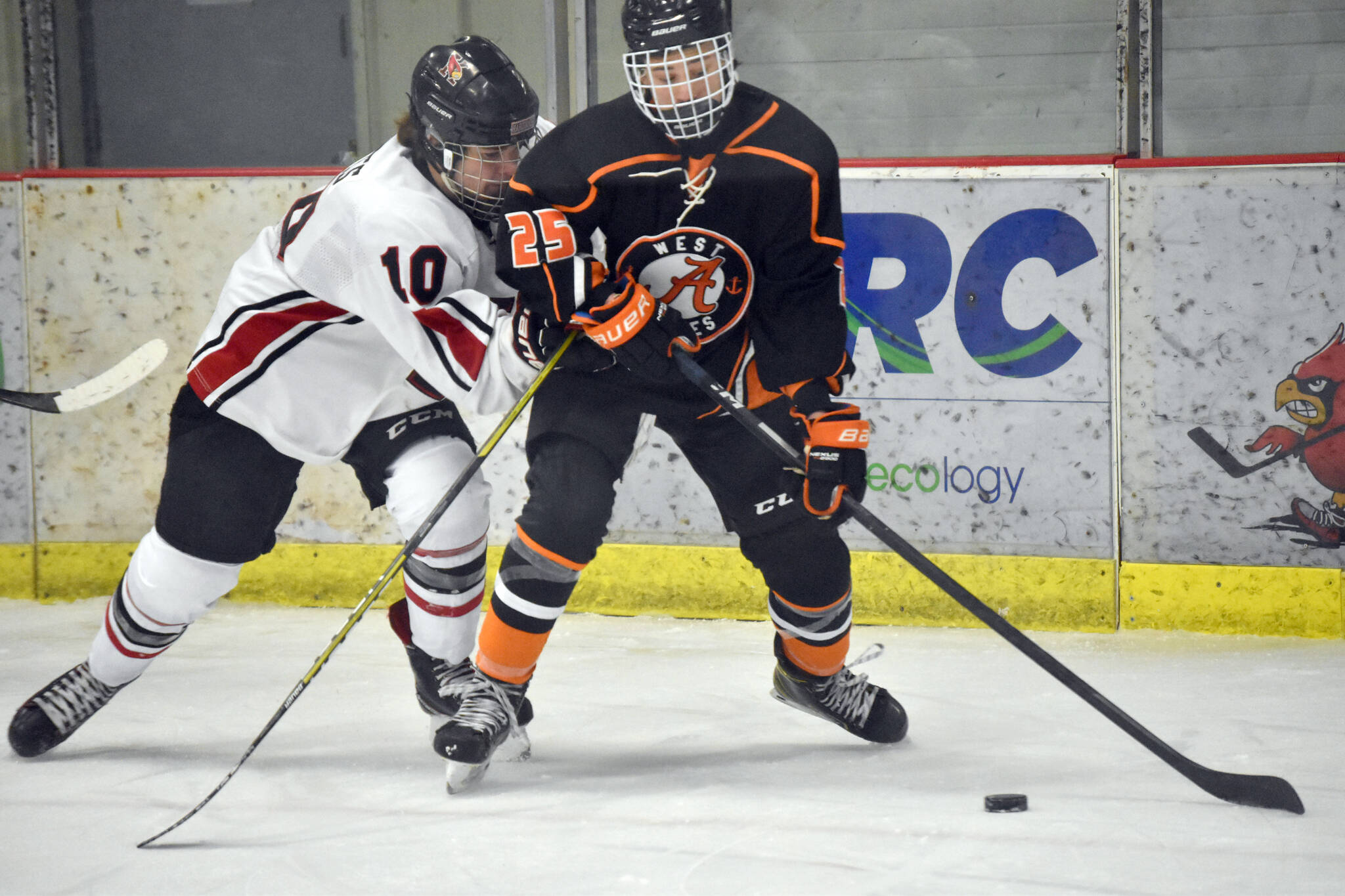 Kenai Central’s Reagan Graves battles for the puck with West’s Henry Sholton on Friday, Jan. 13, 2023, at the Kenai Multi-Purpose Facility in Kenai, Alaska. (Photo by Jeff Helminiak/Peninsula Clarion)