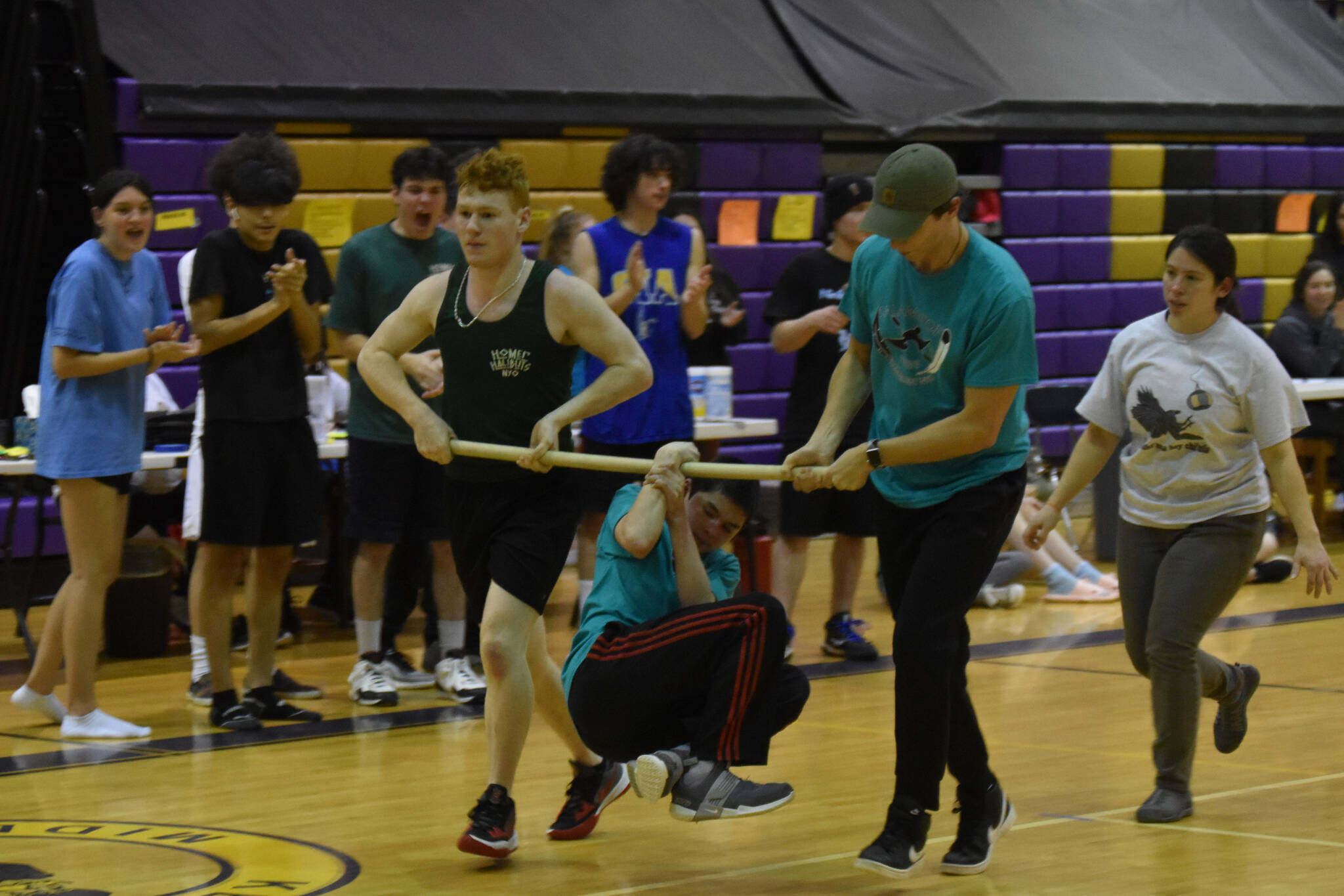 Dakota Butler hangs from a wooden pole by only his wrist as he performs the wrist carry during the Kahtnuht’ana Hey Chi’ula NYO Invitational on Saturday, Jan. 14, 2023, at Kenai Middle School in Kenai, Alaska. Butler held on for more than 200 feet, claiming the gold medal in the event. (Jake Dye/Peninsula Clarion)