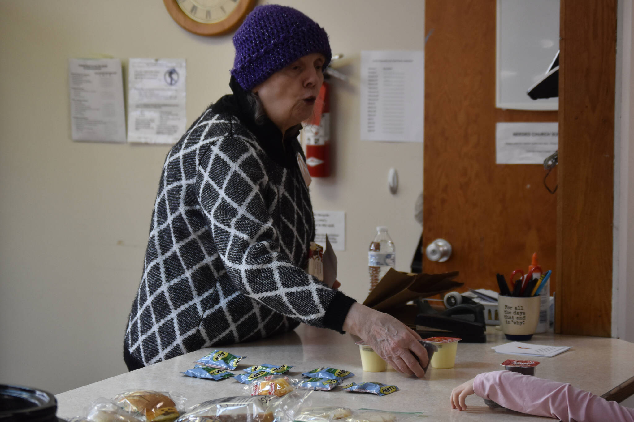 A volunteer passes gummies and pudding to a young girl at Kenai United Methodist Food Pantry in Kenai, Alaska, on Monday, Jan. 23, 2022. (Jake Dye/Peninsula Clarion)