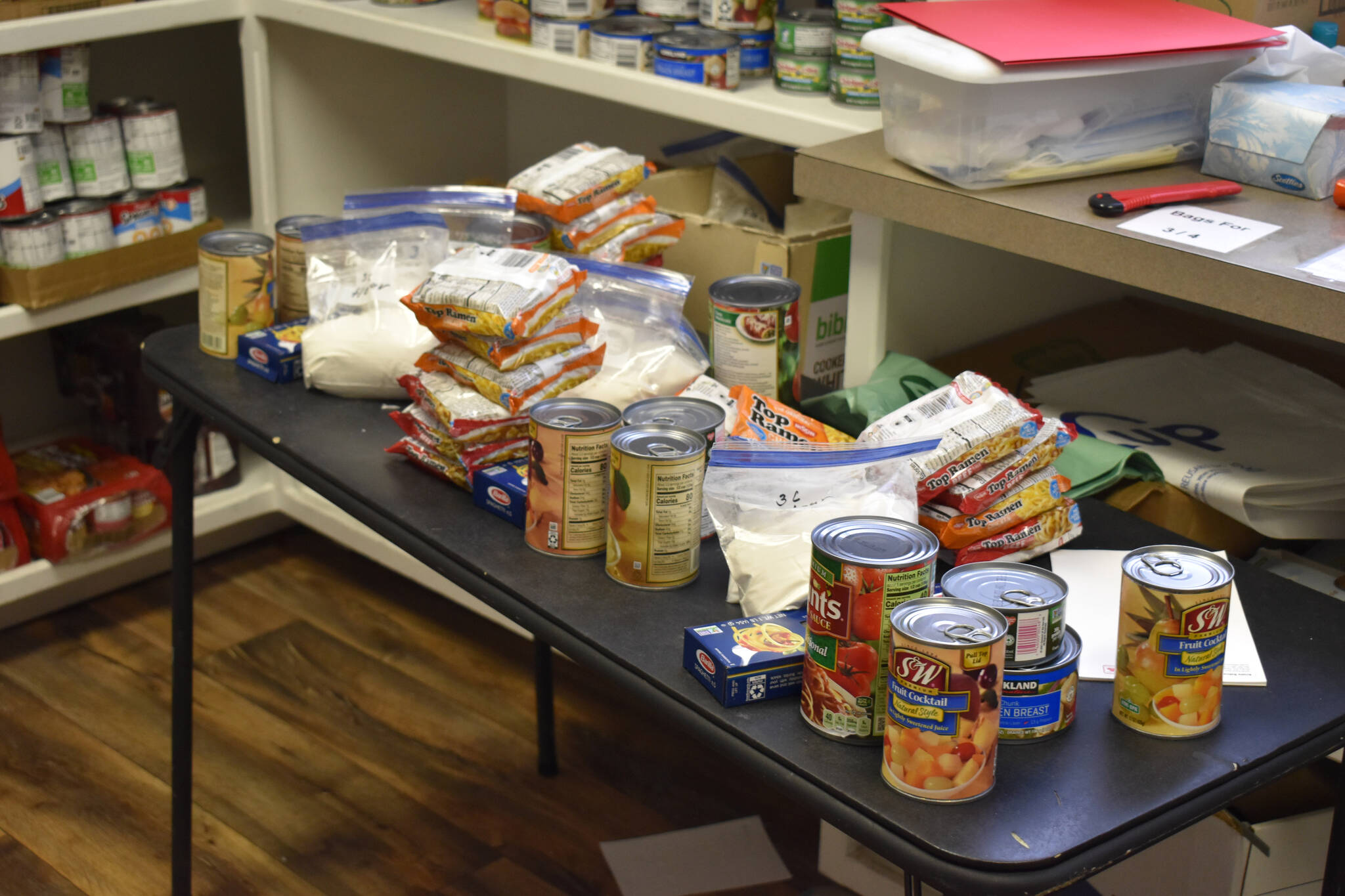 Food is strewn around a table to be bagged and given to those in need at the Kenai United Methodist Food Pantry in Kenai, Alaska, on Monday, Jan. 23, 2022. (Jake Dye/Peninsula Clarion)