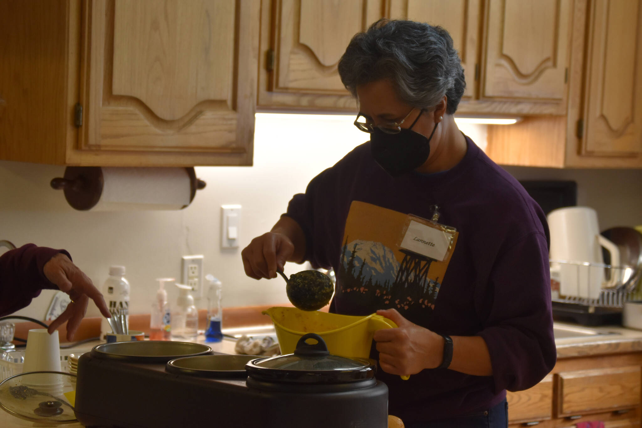A volunteer ladles Hungarian mushroom soup donated by Odie’s at Kenai United Methodist Food Pantry in Kenai, Alaska, on Monday, Jan. 23, 2022. (Jake Dye/Peninsula Clarion)