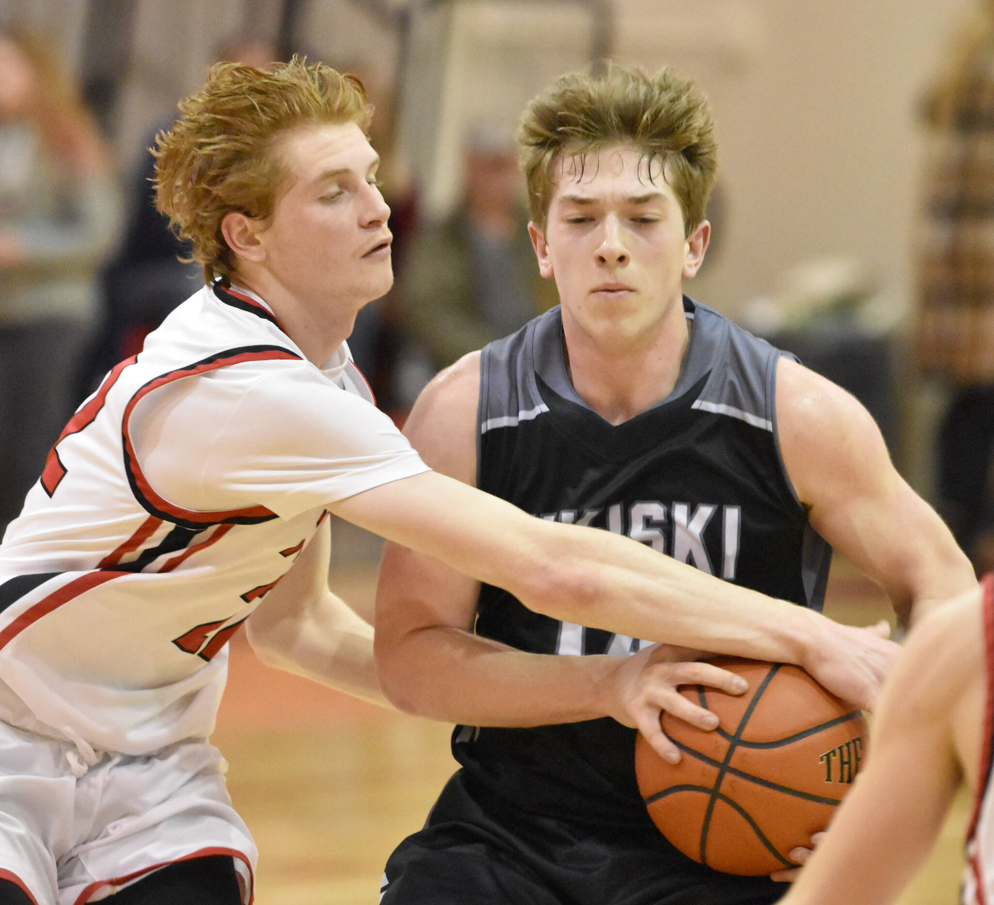 Kenai Central’s Wade James tries to steal the ball from Nikiski’s Braeden Porter on Tuesday, Jan. 31, 2023, at Kenai Central High School in Kenai, Alaska. (Photo by Jeff Helminiak/Peninsula Clarion)