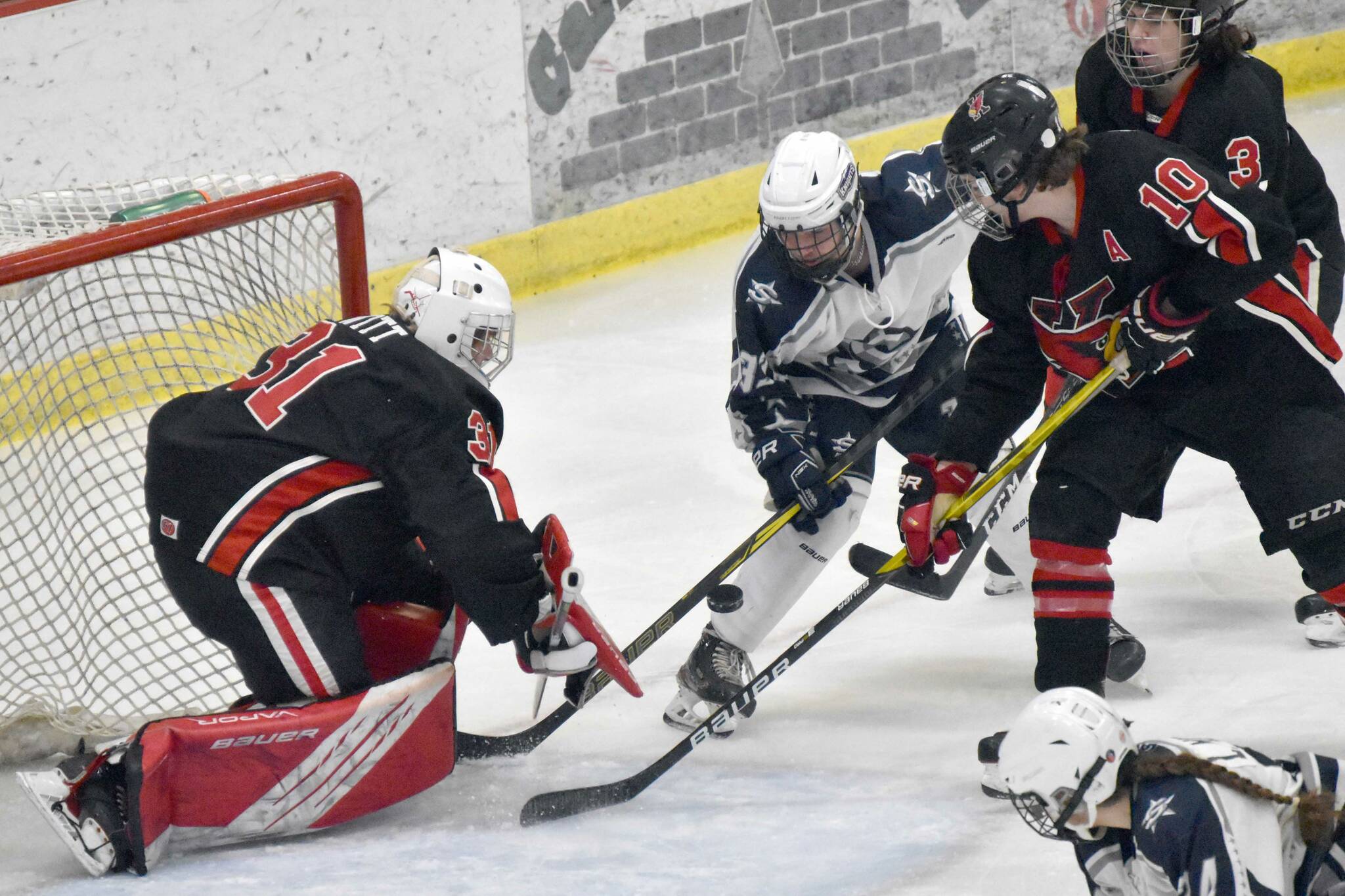 Kenai Central goalie Evyn Witts makes a save on Soldotna's Ezekiel Miller as Kenai's Reagan Graves and Logan Mese defend Friday, Jan. 27, 2023, at the Soldotna Regional Sports Complex in Soldotna, Alaska. (Photo by Jeff Helminiak/Peninsula Clarion)