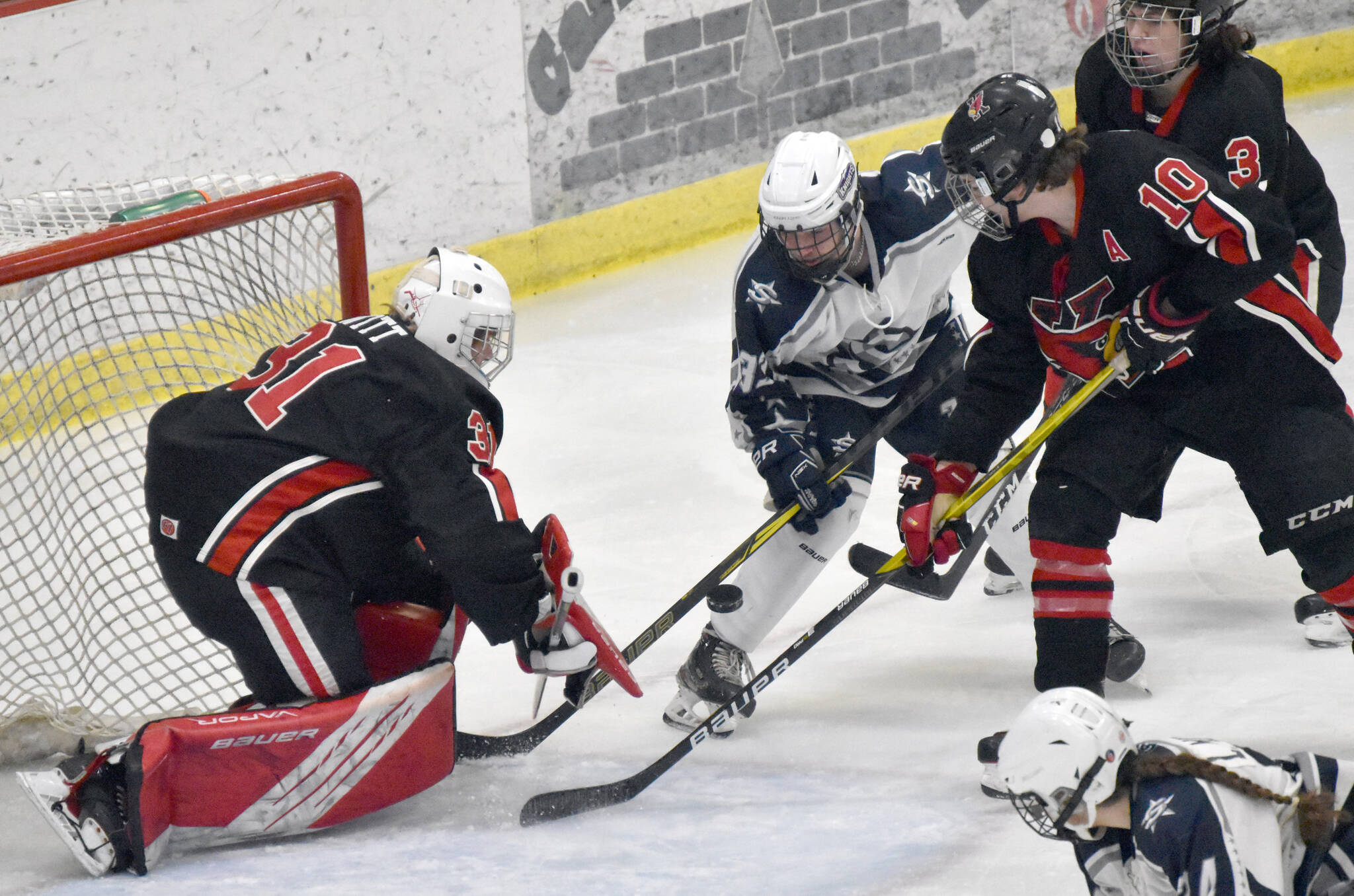 Kenai Central goalie Evyn Witts makes a save on Soldotna’s Ezekiel Miller as Kenai’s Reagan Graves and Logan Mese defend Friday, Jan. 27, 2023, at the Soldotna Regional Sports Complex in Soldotna, Alaska. (Photo by Jeff Helminiak/Peninsula Clarion)