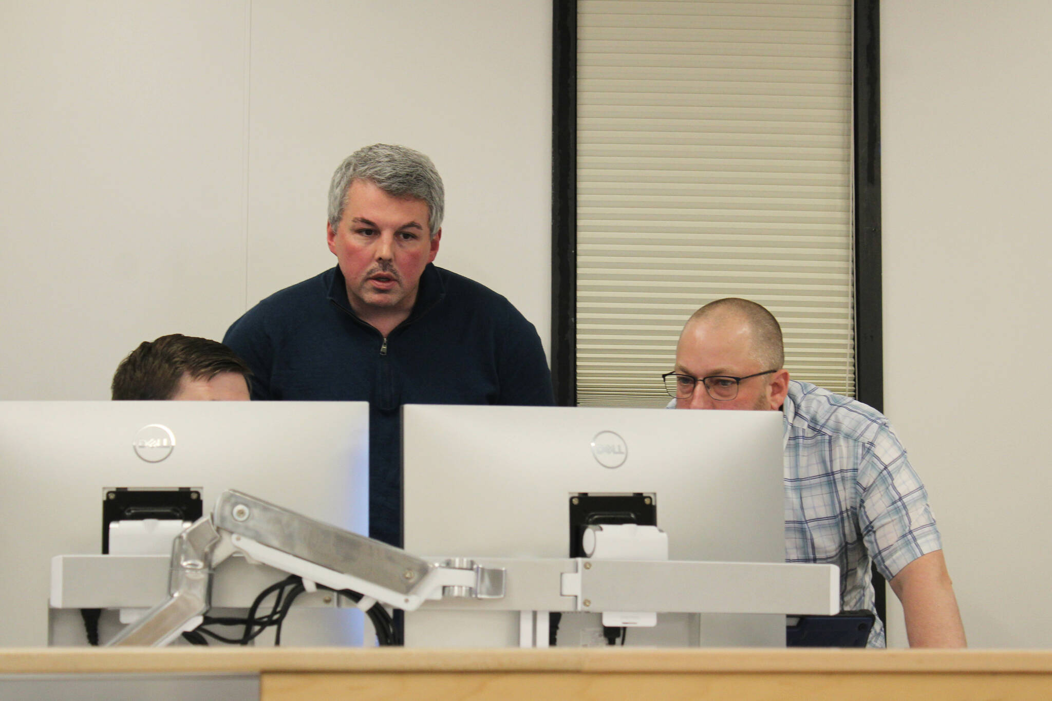 Kenai Peninsula Borough Assembly members Tyson Cox (right) and Richard Derkevorkian (center) discuss an amendment to legislation that raised the borough mayor’s salary at an assembly meeting on Tuesday, Feb. 7, 2023, in Soldotna, Alaska. (Ashlyn O’Hara/Peninsula Clarion)