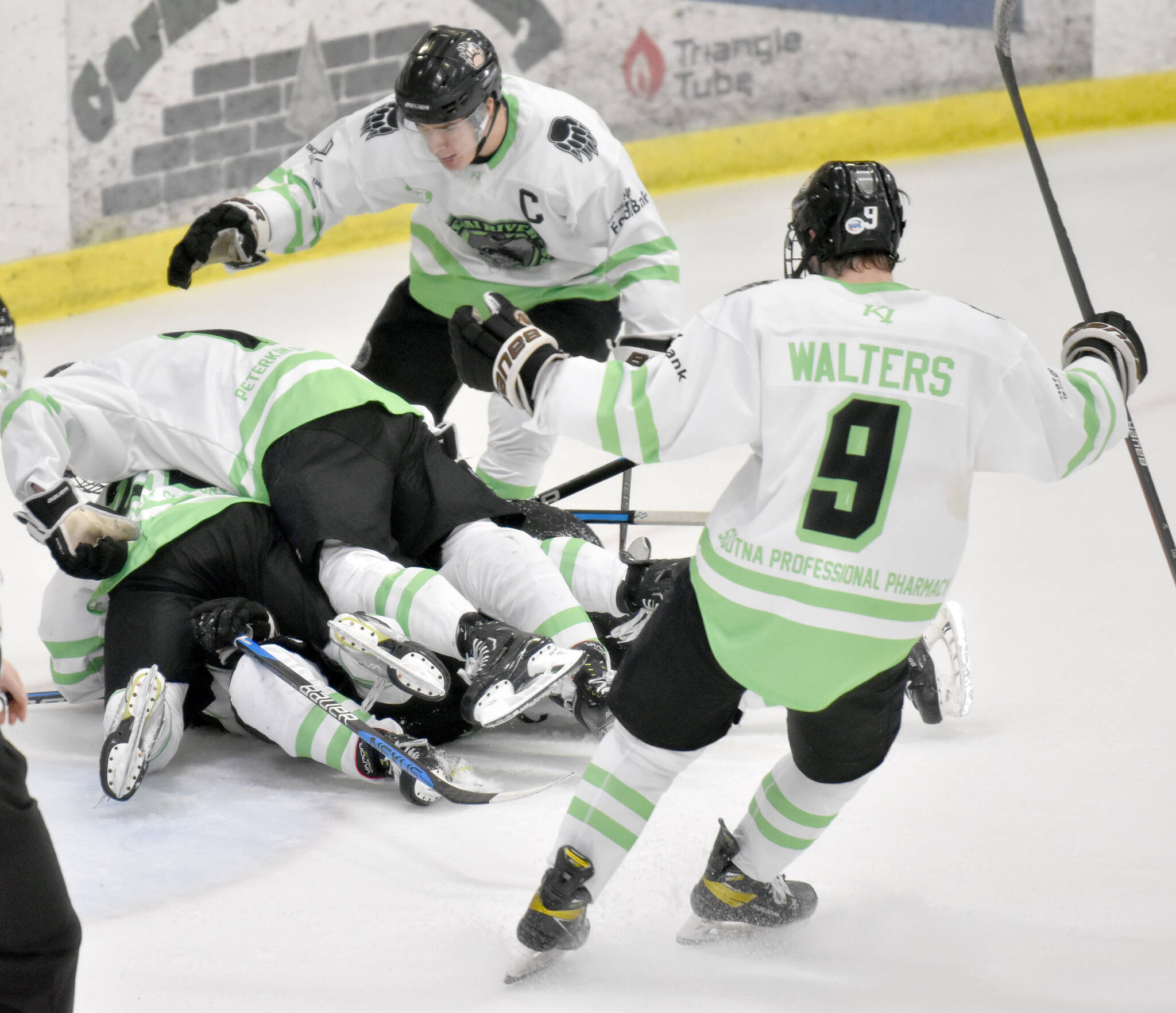 The Kenai River Brown Bears pile on Carson Triggs after he scored the game-winning goal in overtime against the Fairbanks Ice Dogs on Saturday, Feb. 18, 2023, at the Soldotna Regional Sports Complex in Soldotna, Alaska. (Photo by Jeff Helminiak/Peninsula Clarion)