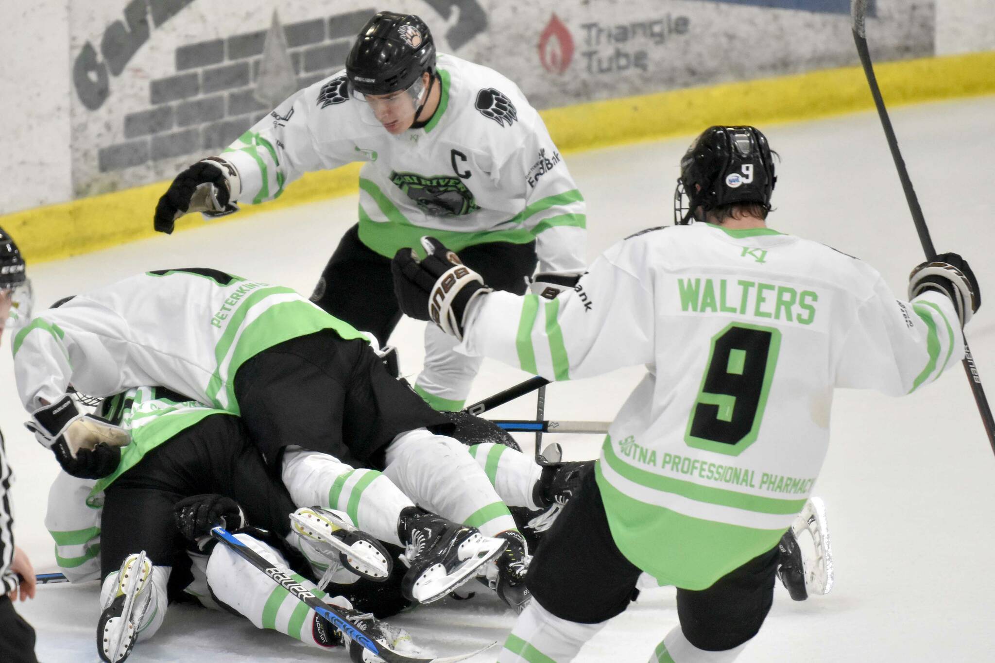 The Kenai River Brown Bears pile on Carson Triggs after he scored the game-winning goal in overtime against the Fairbanks Ice Dogs on Saturday, Feb. 18, 2023, at the Soldotna Regional Sports Complex in Soldotna, Alaska. (Photo by Jeff Helminiak/Peninsula Clarion)