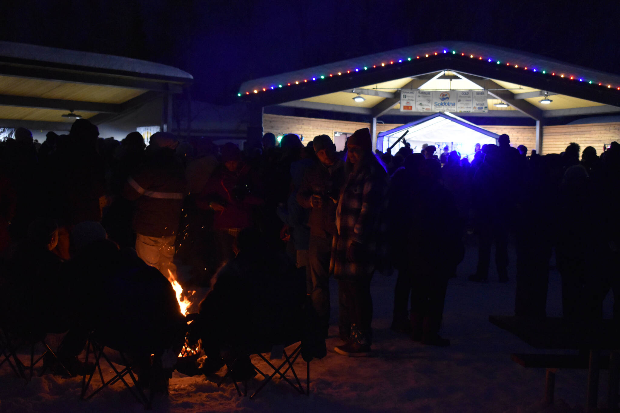 Attendees gather around fires or the stage during Frozen RiverFest on Saturday, Feb. 18, 2023 at Soldotna Creek Park in Soldotna, Alaska. (Jake Dye/Peninsula Clarion)
