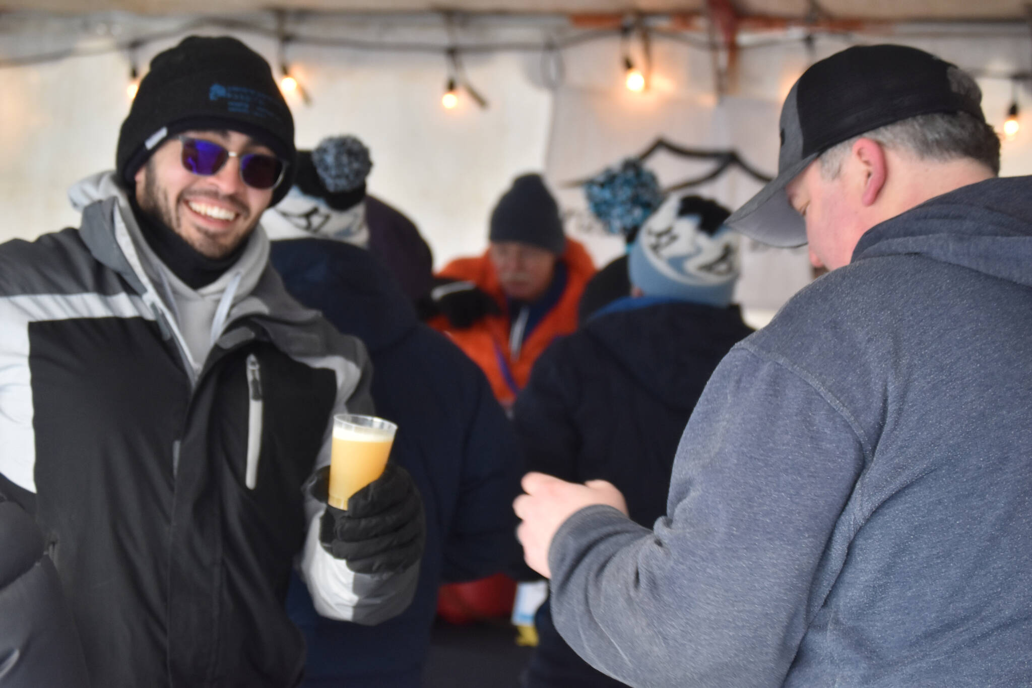 An attendee gets a drink from HooDoo Brewing Company during Frozen RiverFest on Saturday, Feb. 18, 2023 at Soldotna Creek Park in Soldotna, Alaska. (Jake Dye/Peninsula Clarion)