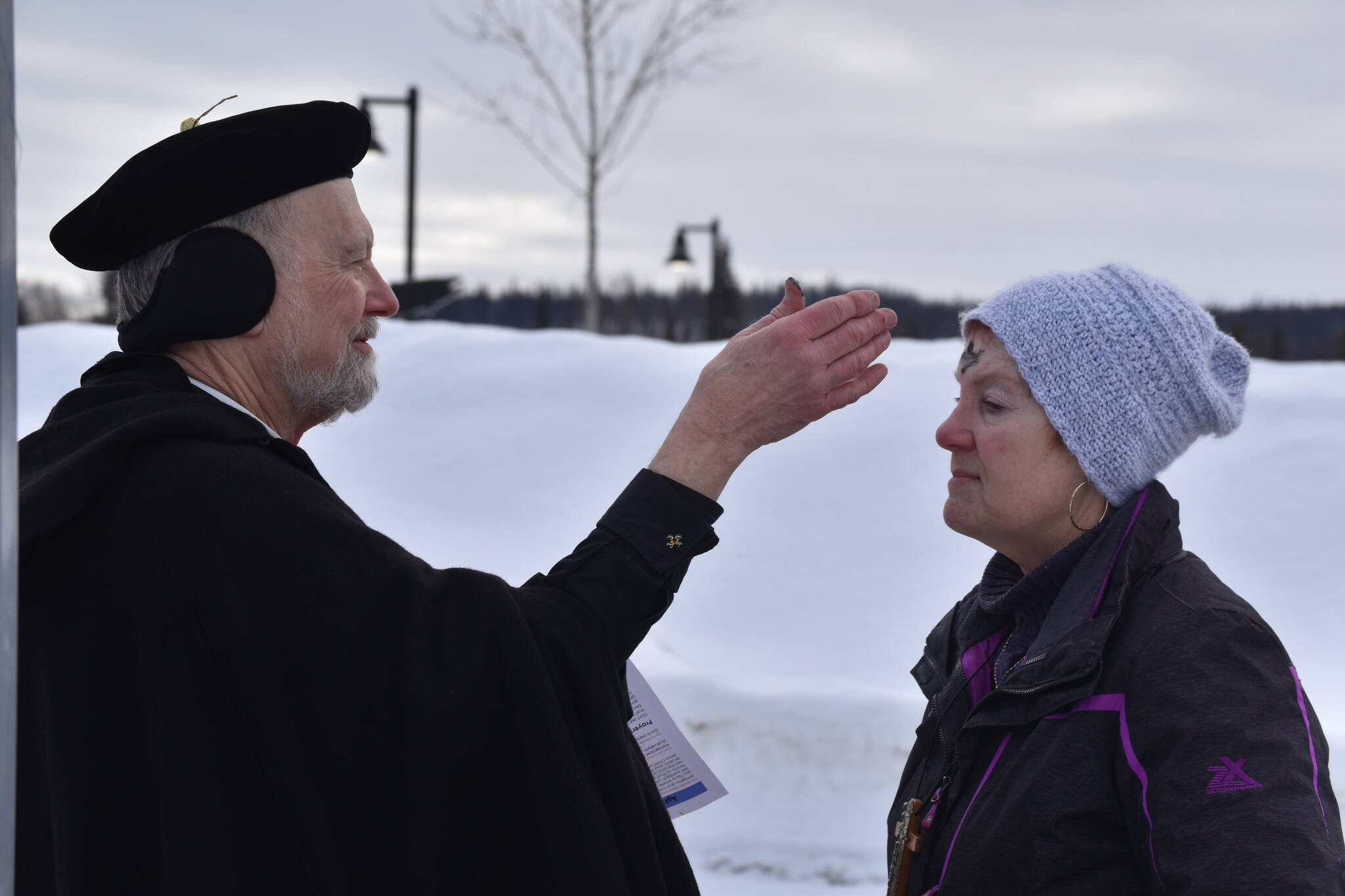 Father Rick Miles applies ashes to Pastor Karen Martin Tichenor’s forehead as they prepare for Ashes to Go! on Wednesday; Feb. 22; 2023 at Soldotna Creek Park in Soldotna; Alaska. (Jake Dye/Peninsula Clarion)