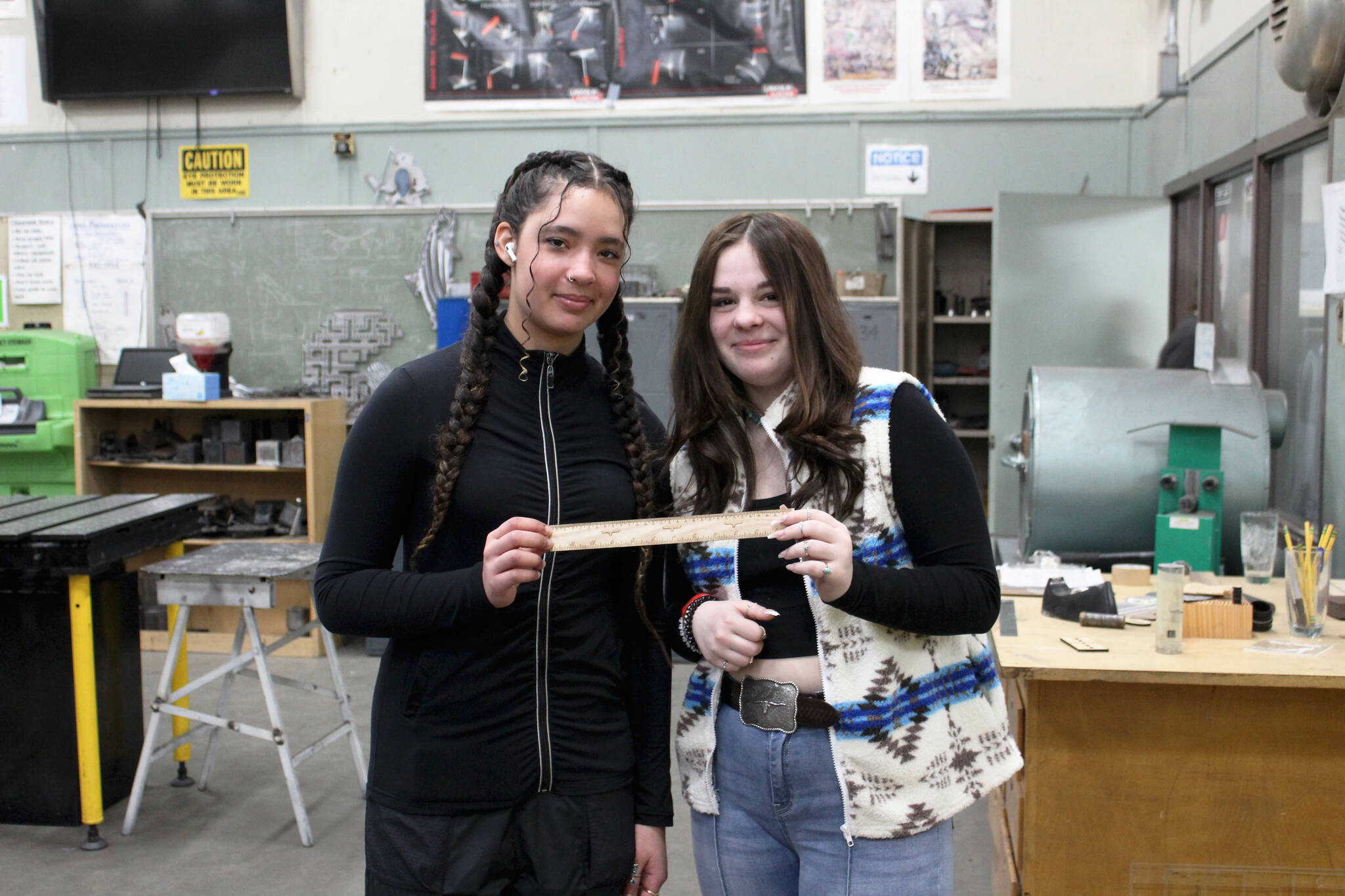 Kenai Central High School freshmen Franchesca Wingster (left) and Olivia McDonald (right) hold a ruler they created in a shop class on Wednesday, Feb. 22, 2023 in Kenai, Alaska (Ashlyn O’Hara/Peninsula Clarion)