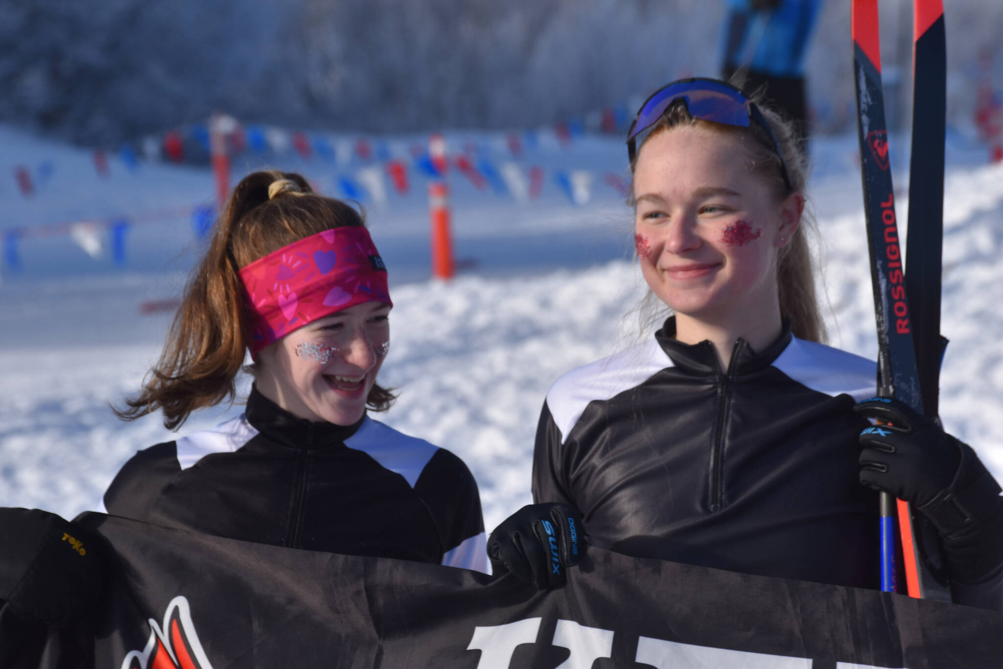 Kenai Central skiers Mya Taylor and Emily Moss celebrate finishing the girls 4x3.5-kilometer relay, their last race at the ASAA State Nordic Ski Championships at Kincaid Park in Anchorage, Alaska, on Saturday, Feb. 25, 2023. (Jake Dye/Peninsula Clarion)