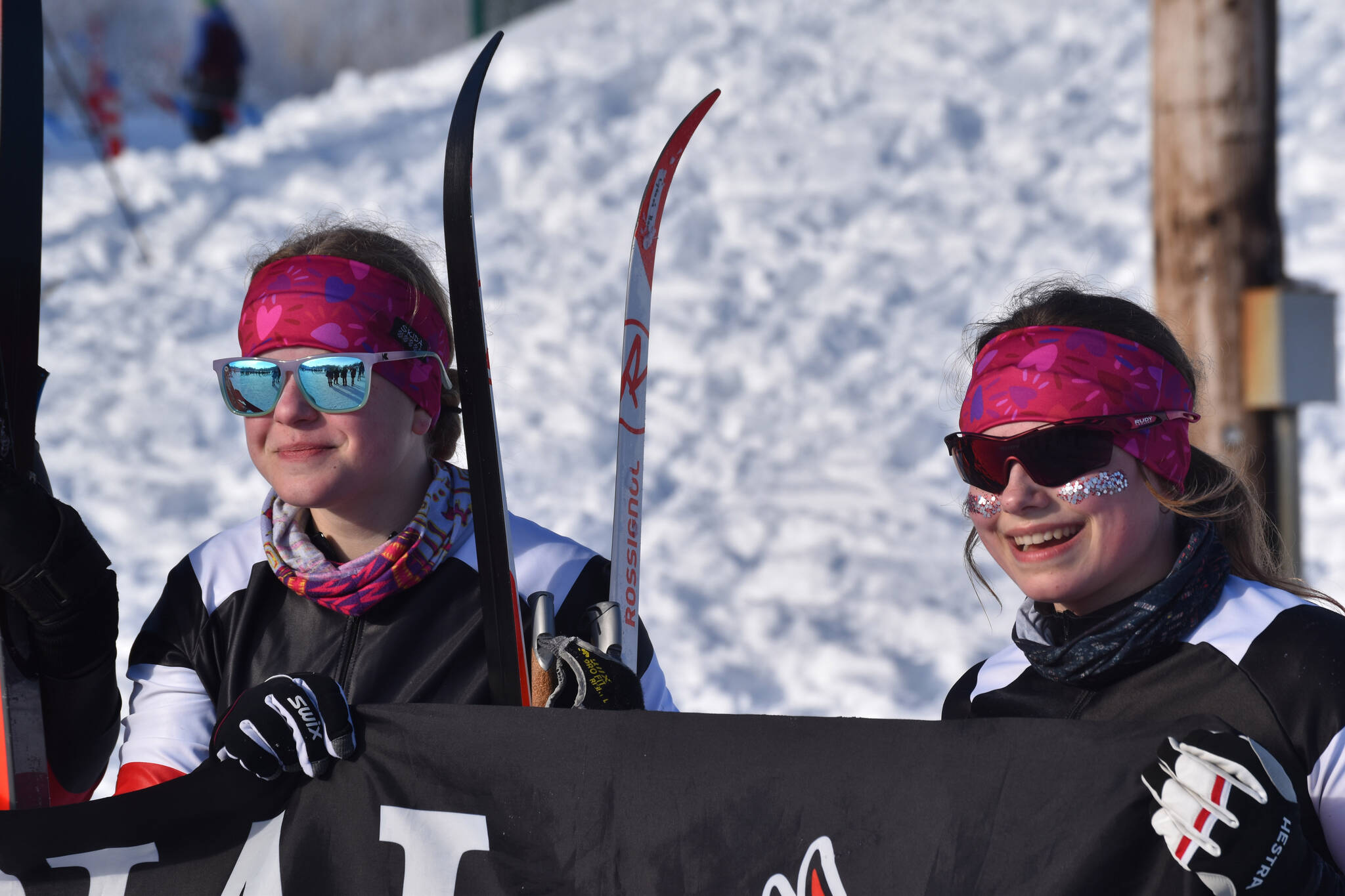 Kenai Central skiers Lynnea Hack and Madison McDonald celebrate finishing the girls 4x3.5-kilometer relay, their last race at the ASAA State Nordic Ski Championships at Kincaid Park in Anchorage, Alaska, on Saturday, Feb. 25, 2023. (Jake Dye/Peninsula Clarion)