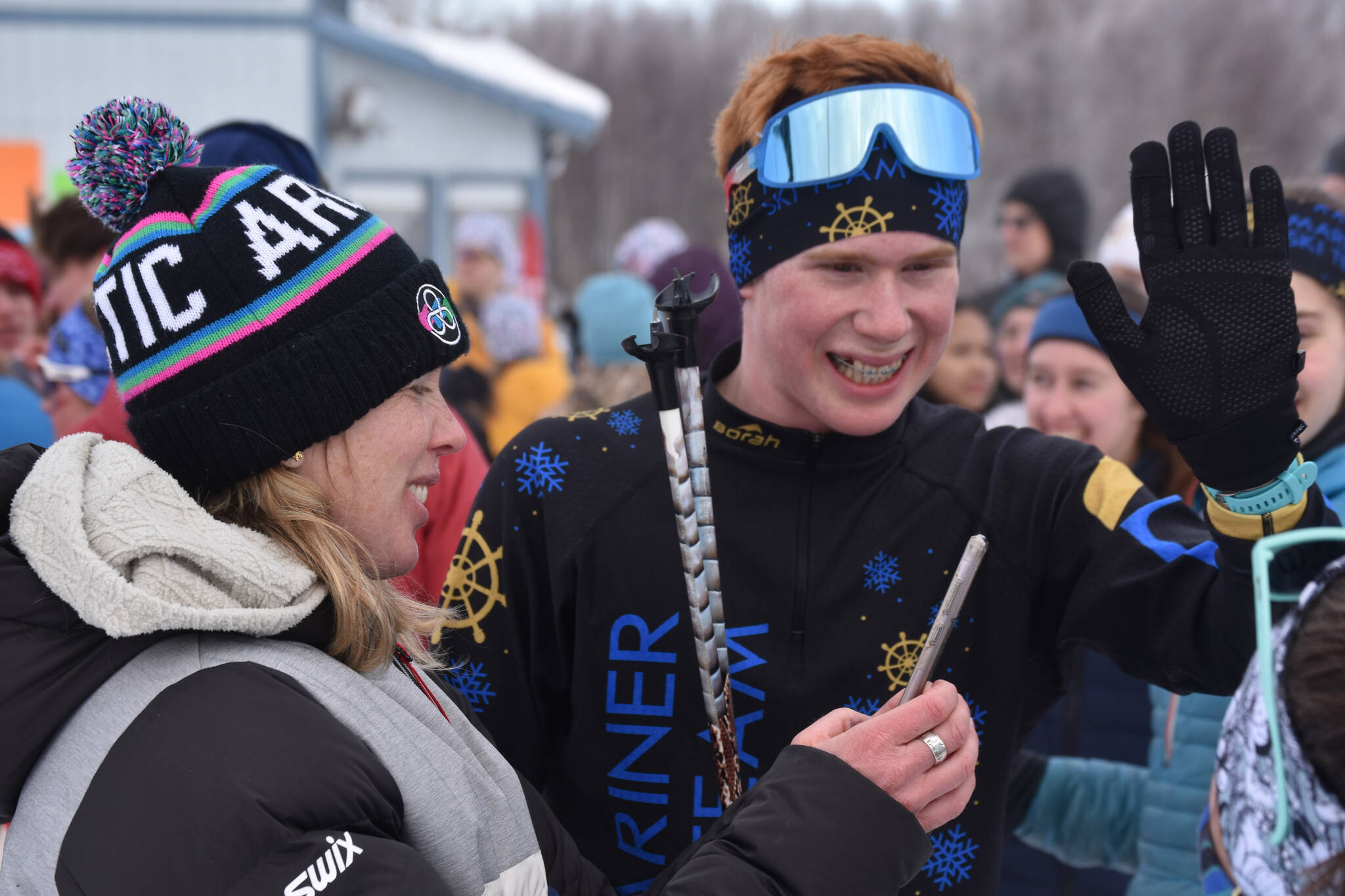 Jody Goodrich reaches out for a high five and smiles alongside Jessie Goodrich, his mother and coach, after he completed the final leg of the boys 4x5-kilometer relay and secured the Homer boys’ program-first Division II win at the ASAA State Nordic Ski Championships at Kincaid Park in Anchorage, Alaska, on Saturday, Feb. 25, 2023. (Jake Dye/Peninsula Clarion)