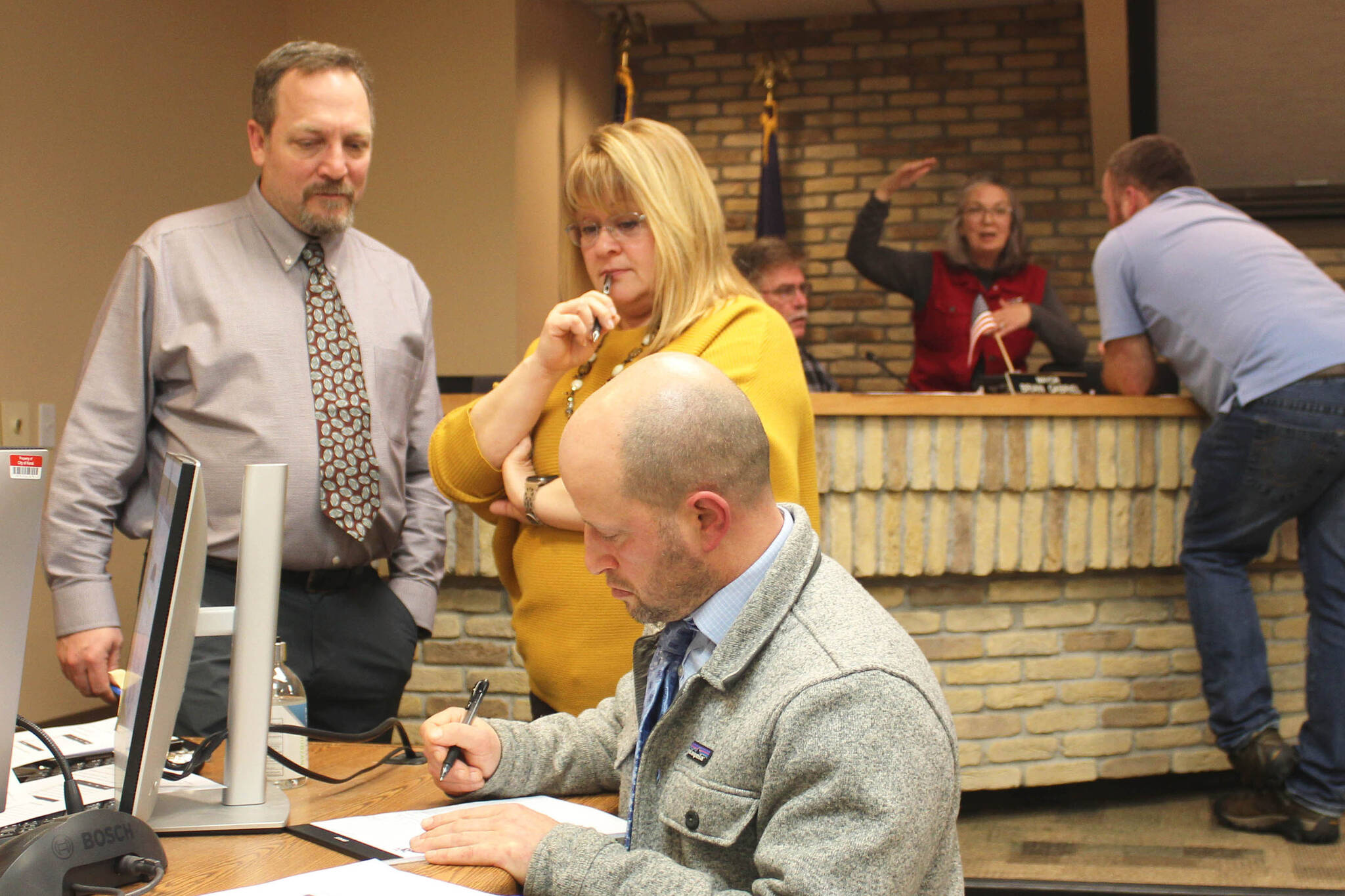 Foreground, from left: Kenai City Manager Terry Eubank and Kenai City Clerk Shellie Saner watch as Kenai City Attorney Scott Bloom wordsmiths an amendment to an ordinance during a council meeting on Wednesday at Kenai City Hall, March 1, 2023, in Kenai, Alaska. Background from left: Kenai Mayor Brian Gabriel, Deborah Sounart and Alex Douthit discuss the legislation, which allows more city residents to keep chickens on their property. (Ashlyn O’Hara/Peninsula Clarion)