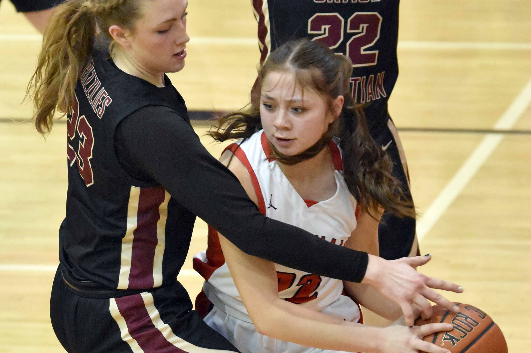 Kenai Central's Emilee Wilson looks to escape the trap of Grace Christian's Sophie Lentfer and Olivia Jones on Friday, March 3, 2023, at Kenai Central High School in Kenai, Alaska. (Photo by Jeff Helminiak/Peninsula Clarion)