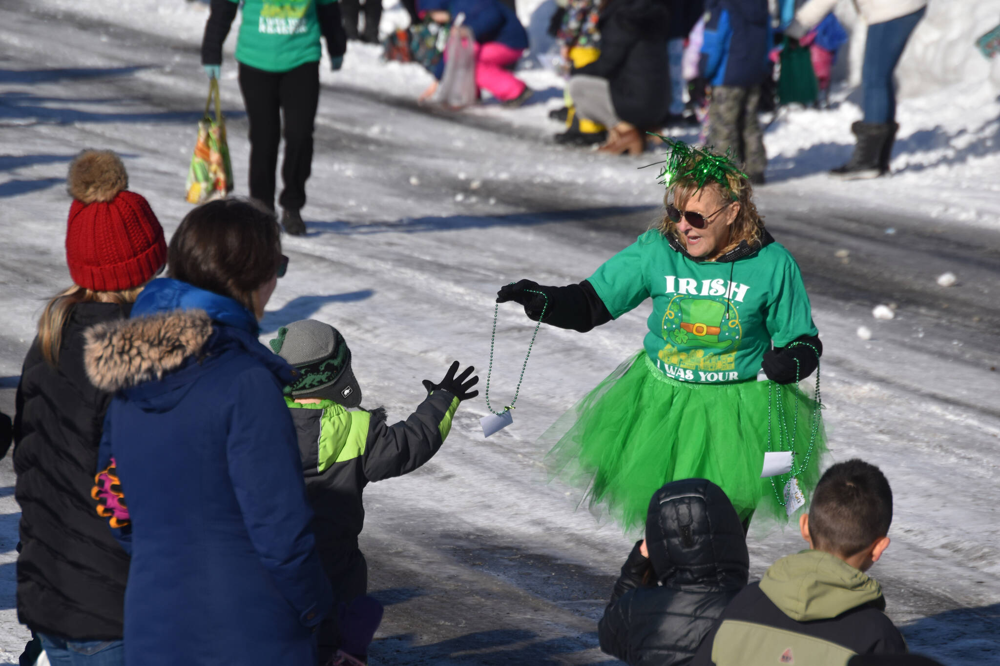 Green bead necklaces are passed out as the 32nd annual Sweeney’s St. Patrick’s Day Parade proceeds down Fireweed Street in Soldotna, Alaska on Friday, March 17, 2023. (Jake Dye/Peninsula Clarion)