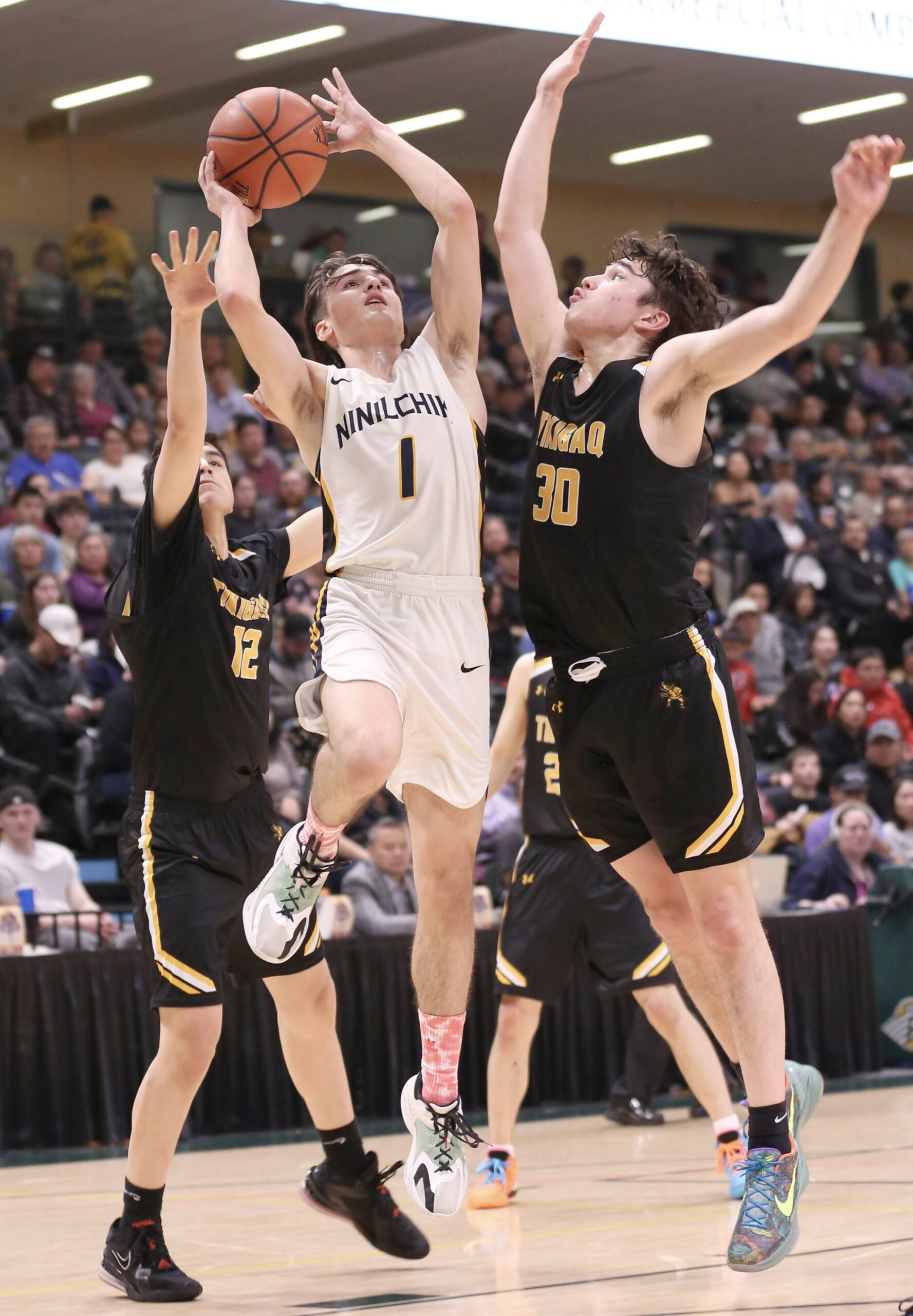 Ninilchik’s Rowan Mahoney goes up for a shot against Tikigaq’s Micah Kinneeveauk and Aqquilluk Hank in the Class 2A boys state championship Saturday, March 18, 2023, at the Alaska Airlines Center in Anchorage, Alaska. (Photo courtesy of Robin Moore)