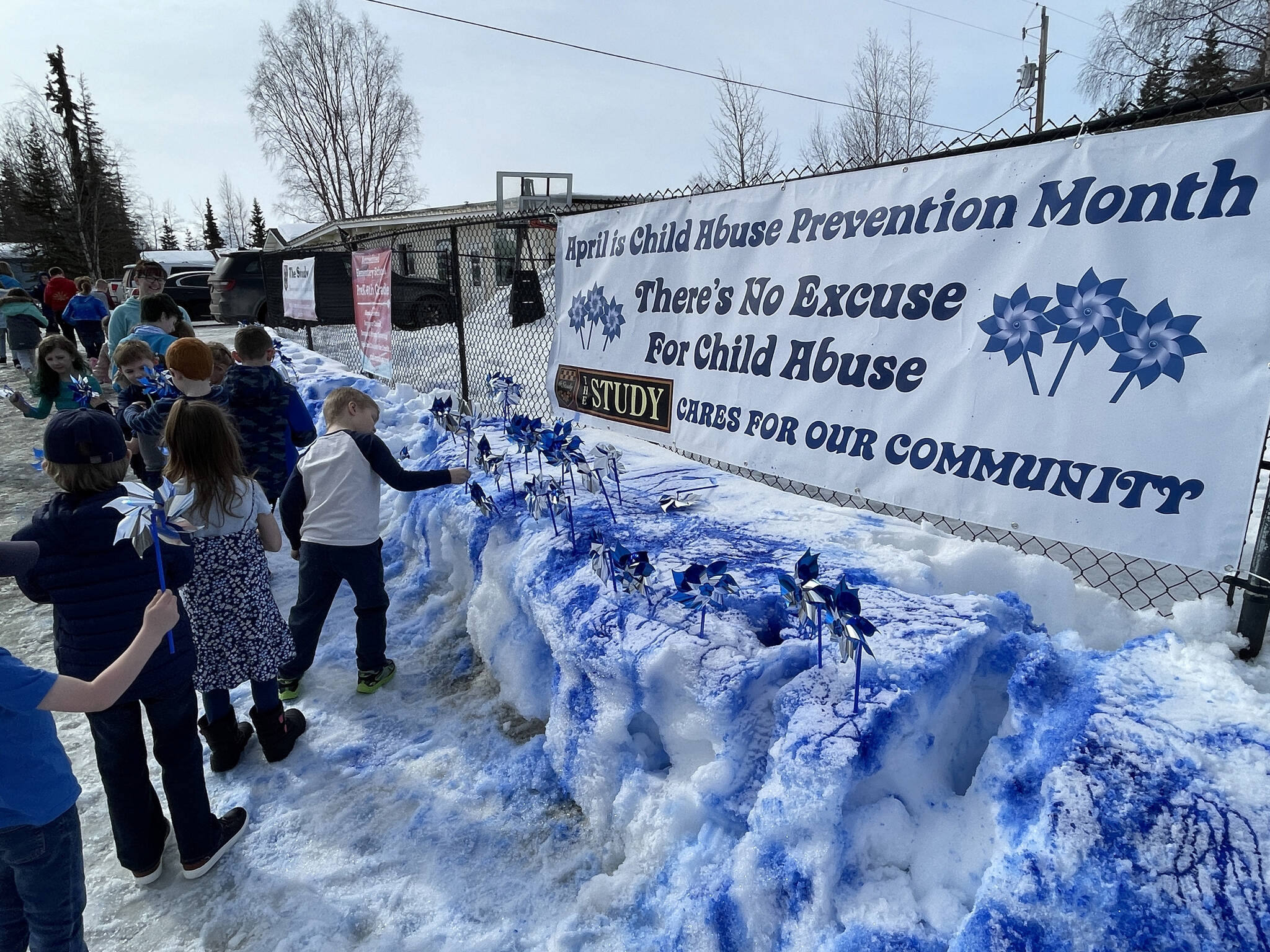 Students place pinwheels in snow painted a vibrant blue at The Study in Soldotna, Alaska, as they commemorate Go Blue Day on Friday, March 31, 2023, to kick off Child Abuse Prevention Month. (Jake Dye/Peninsula Clarion)