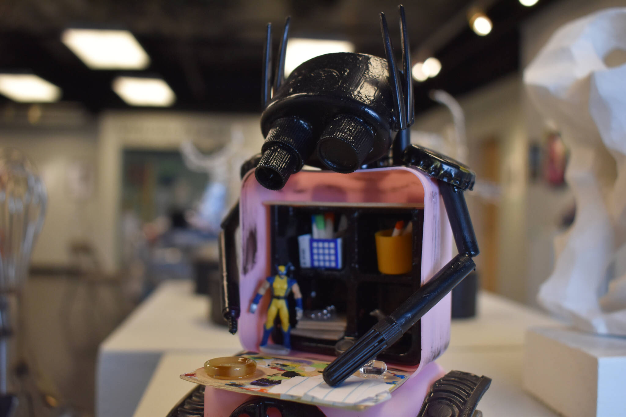 A sculpture of a small robotic figure rests on a plinth, their torso filled with art supplies and Wolverine, at the Kenai Art Center in Kenai, Alaska on Wednesday, April 5, 2023, in preparation for the debut of the 32nd Annual Kenai Peninsula Borough School District Visual Feast. (Jake Dye/Peninsula Clarion)