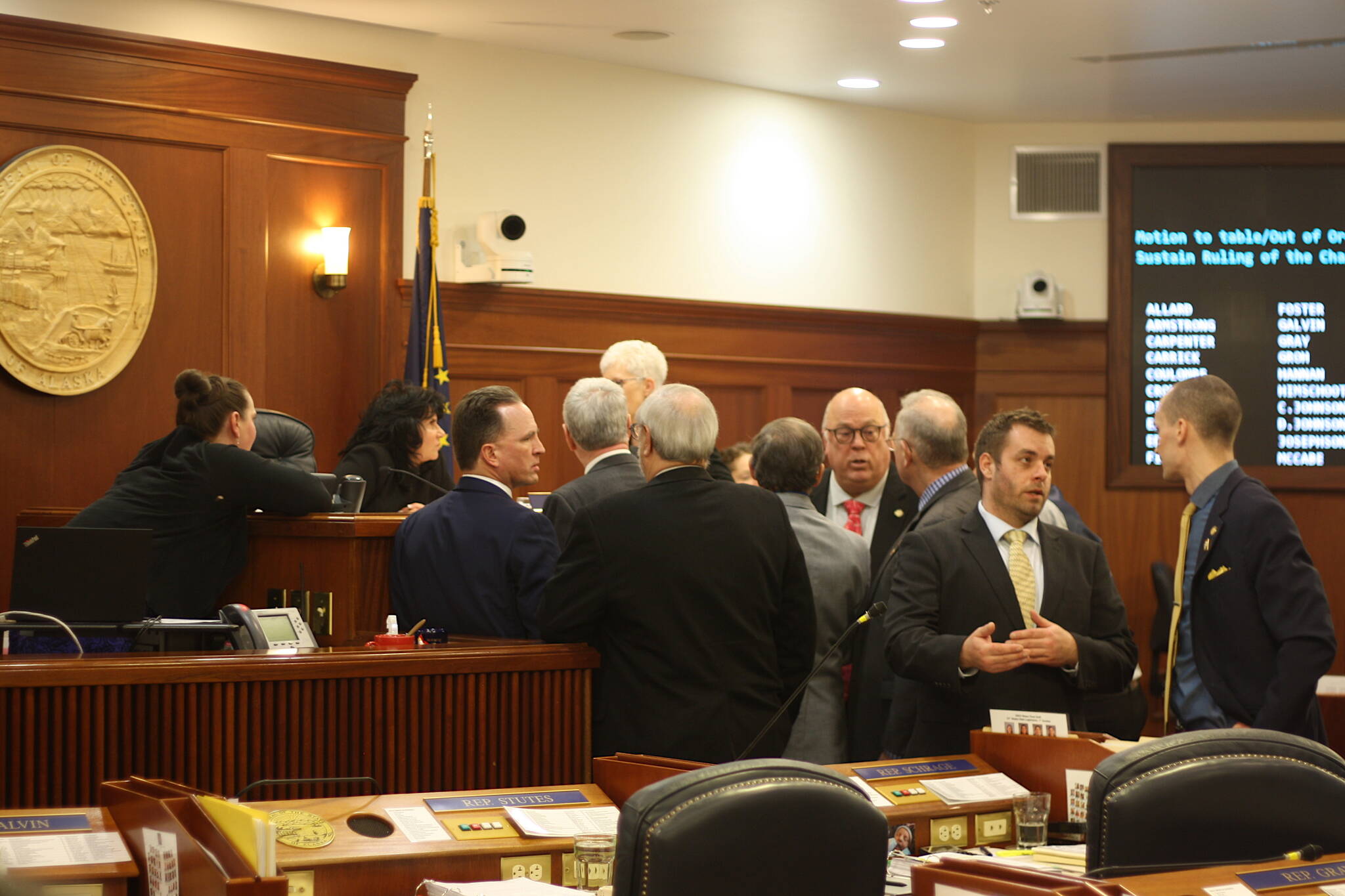 Members of the House majority and House Minority Leader Calvin Schrage, I-Anchorage, at far right, cluster around the podium of House Speaker Cathy Tilton during a break in Wednesday’s floor session that featured an hours-long standoff involving an increase in education funding. (Mark Sabbatini / Juneau Empire)