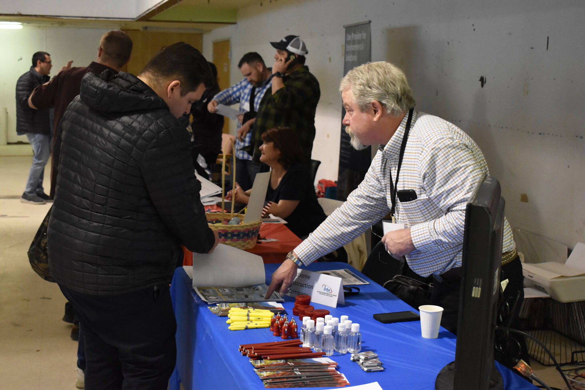 Randy Barnes, vice president of Alaska Building at Osborne Construction Company, points to information about a job opening at the Kenai Peninsula Job and Career Fair on Thursday, April 6, 2023, at the Old Carrs Mall in Kenai, Alaska. (Jake Dye/Peninsula Clarion)