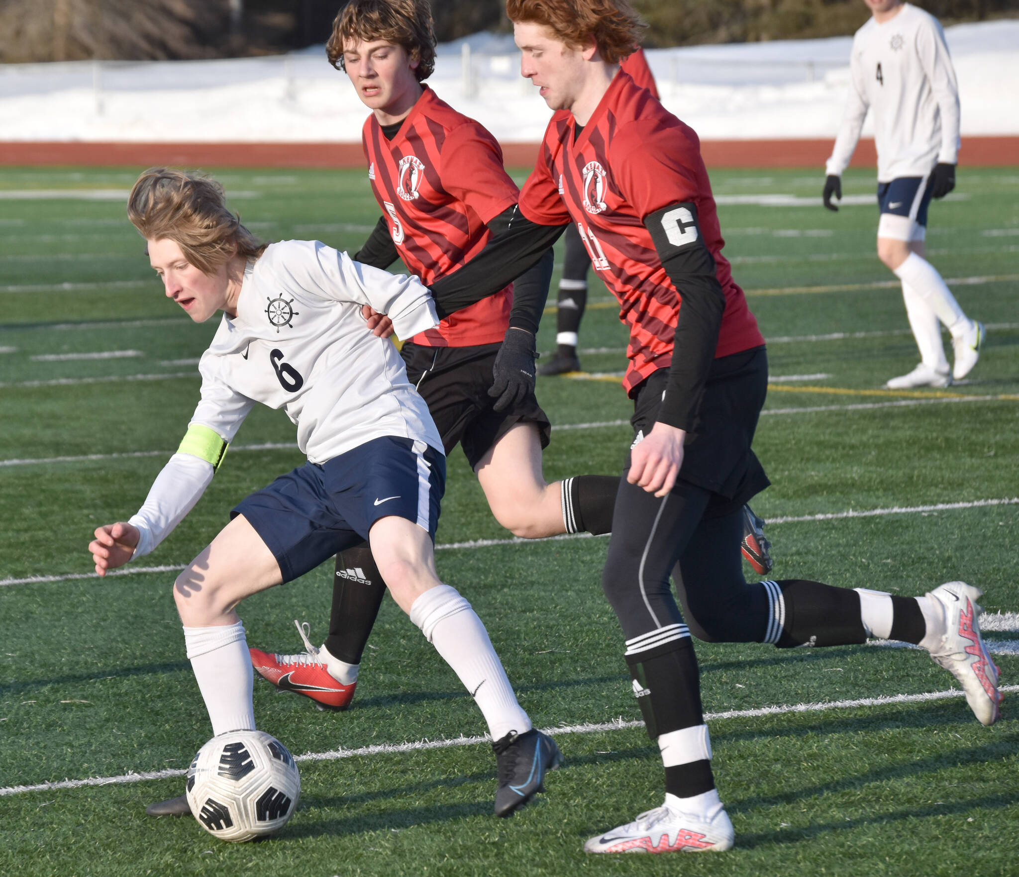 Homer's Owen Pitzman shields the ball from Kenai Central's Wade James on Thursday, April 6, 2023, at Ed Hollier Field at Kenai Central High School in Kenai, Alaska. (Photo by Jeff Helminiak/Peninsula Clarion)