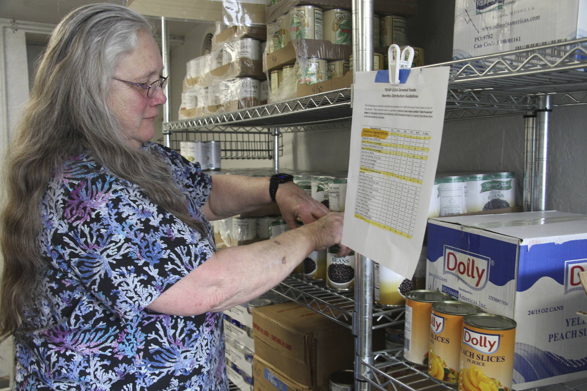Rose Carney organizes supplies at the food pantry at Harvest Christian Fellowship Church in Eagle River, Alaska, on April 17, 2023. Carney and thousands of Alaskans who depend on government assistance have not received food stamps for months, exacerbating a hunger crisis. (AP Photo/Mark Thiessen)