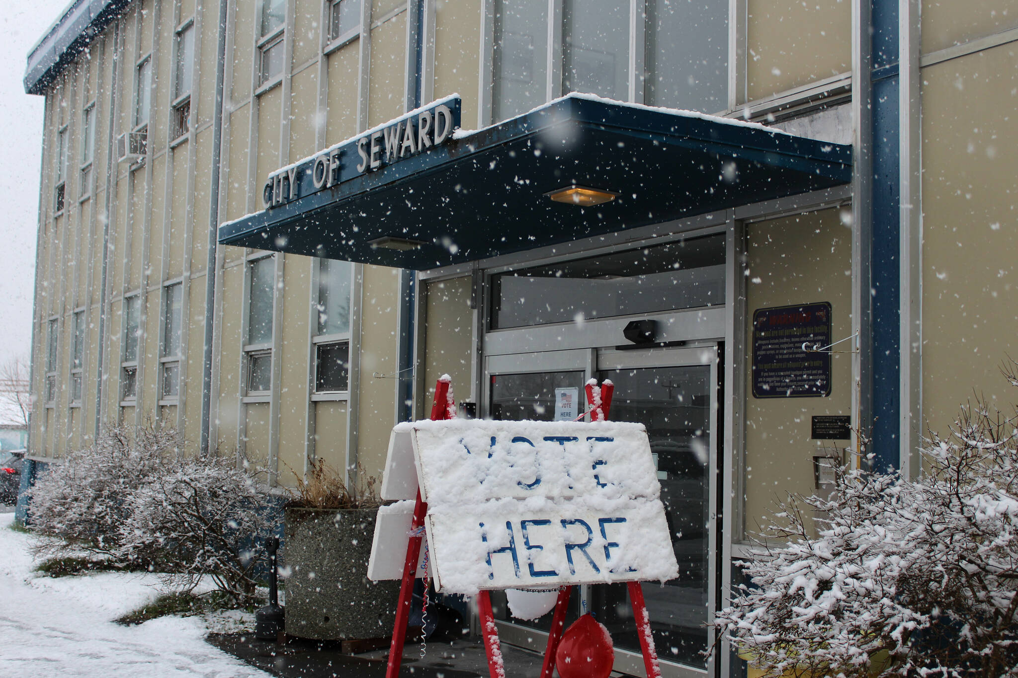 Snow falls on a “vote here” sign outside of Seward City Hall on Tuesday, May 2, 2023, in Seward, Alaska. Residents voted in a special election to determine whether or not to sell the city’s electric utility and to change the city’s residency requirements for city manager. (Ashlyn O’Hara/Peninsula Clarion)