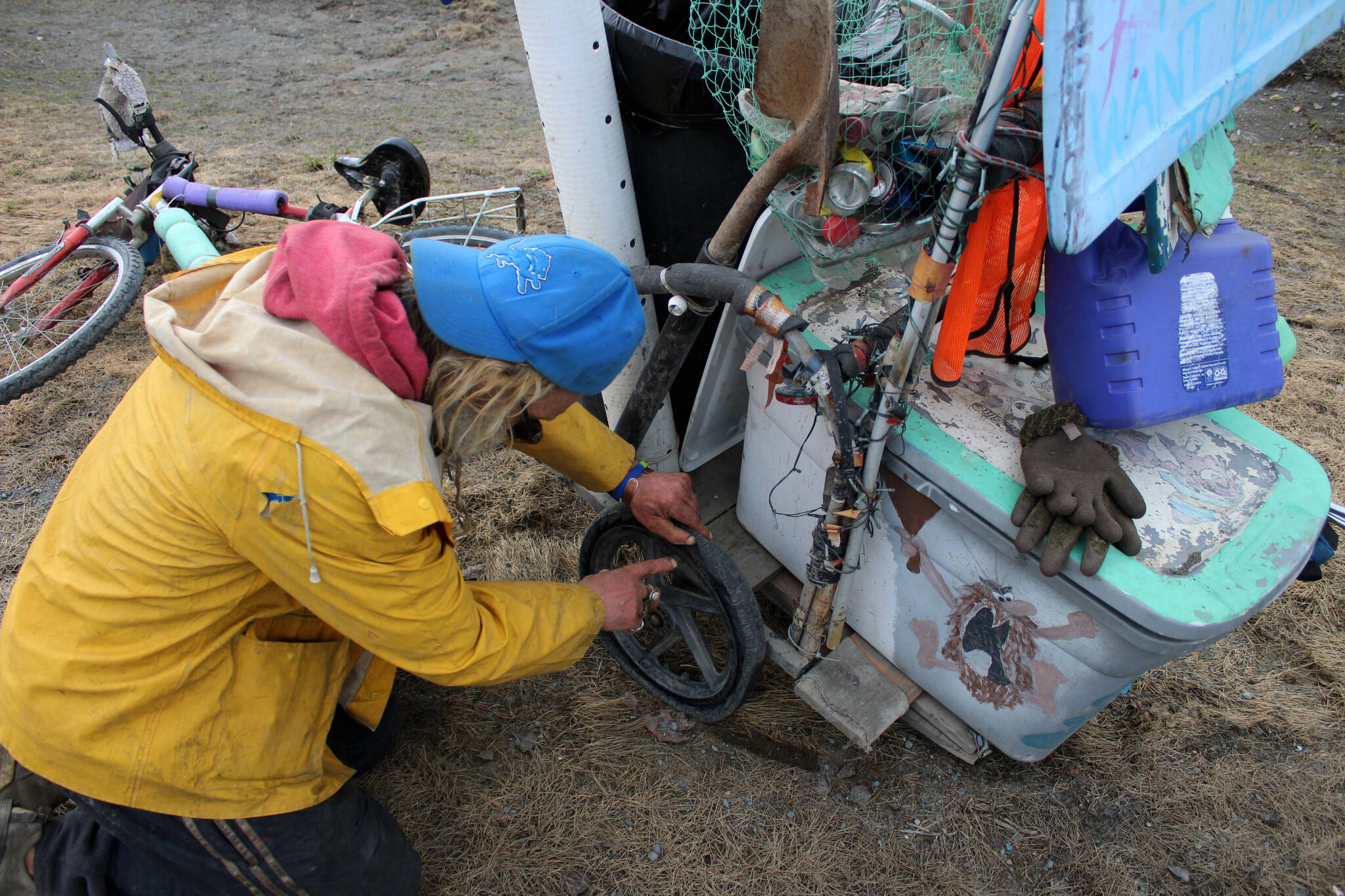 White Rainbow examines a flat tire on his bike at a gas station on Wednesday, May 3, 2023 near Sterling, Alaska. (Ashlyn OHara/Peninsula Clarion)