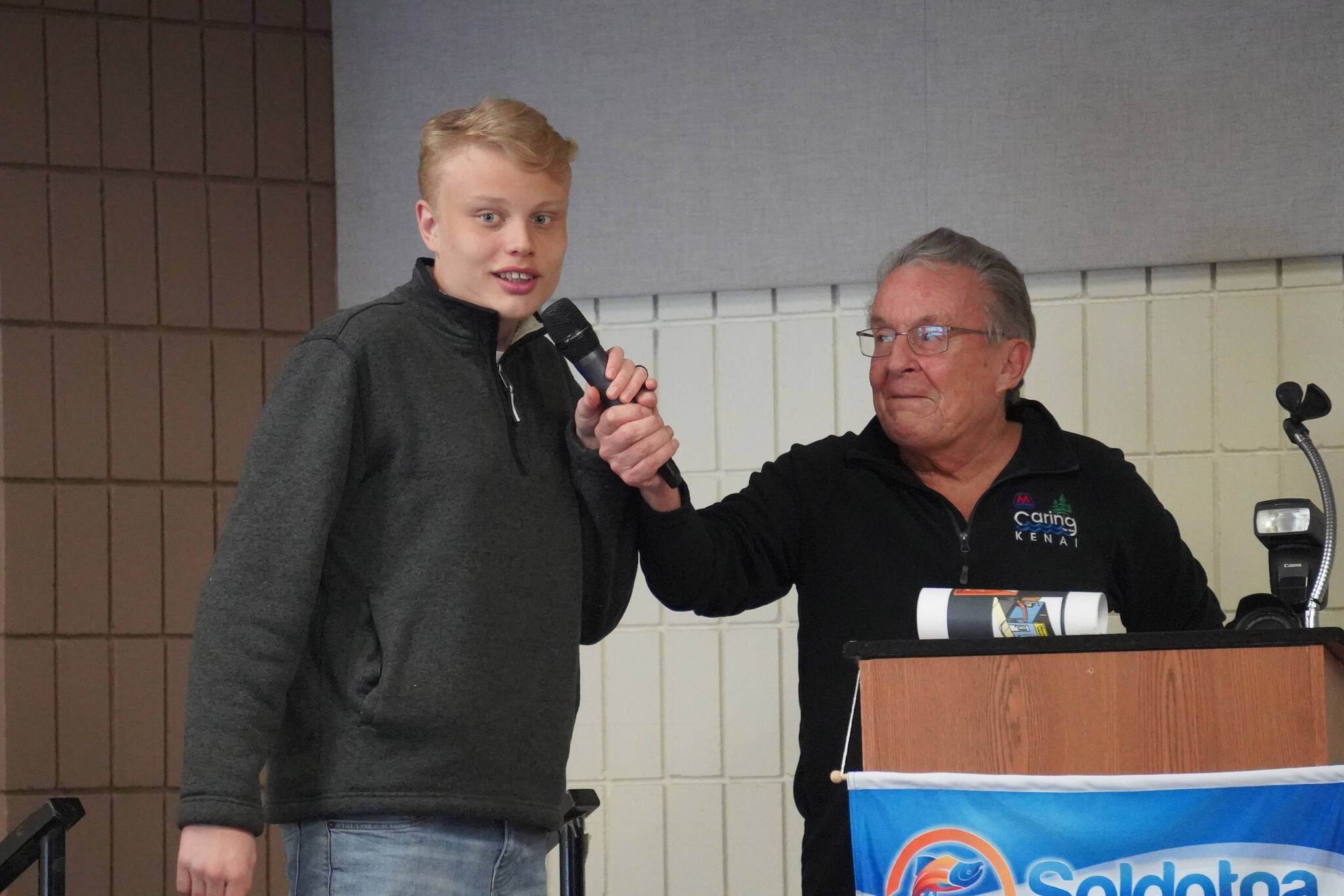 Liam Bartholomew, of Cook Inlet Academy, is introduced by Merrill Sikorski at the Caring for the Kenai Awards Celebration held during a Joint Chamber Luncheon on Wednesday, May 3, 2023, at the Soldotna Regional Sports Complex in Soldotna, Alaska. (Jake Dye/Peninsula Clarion)
