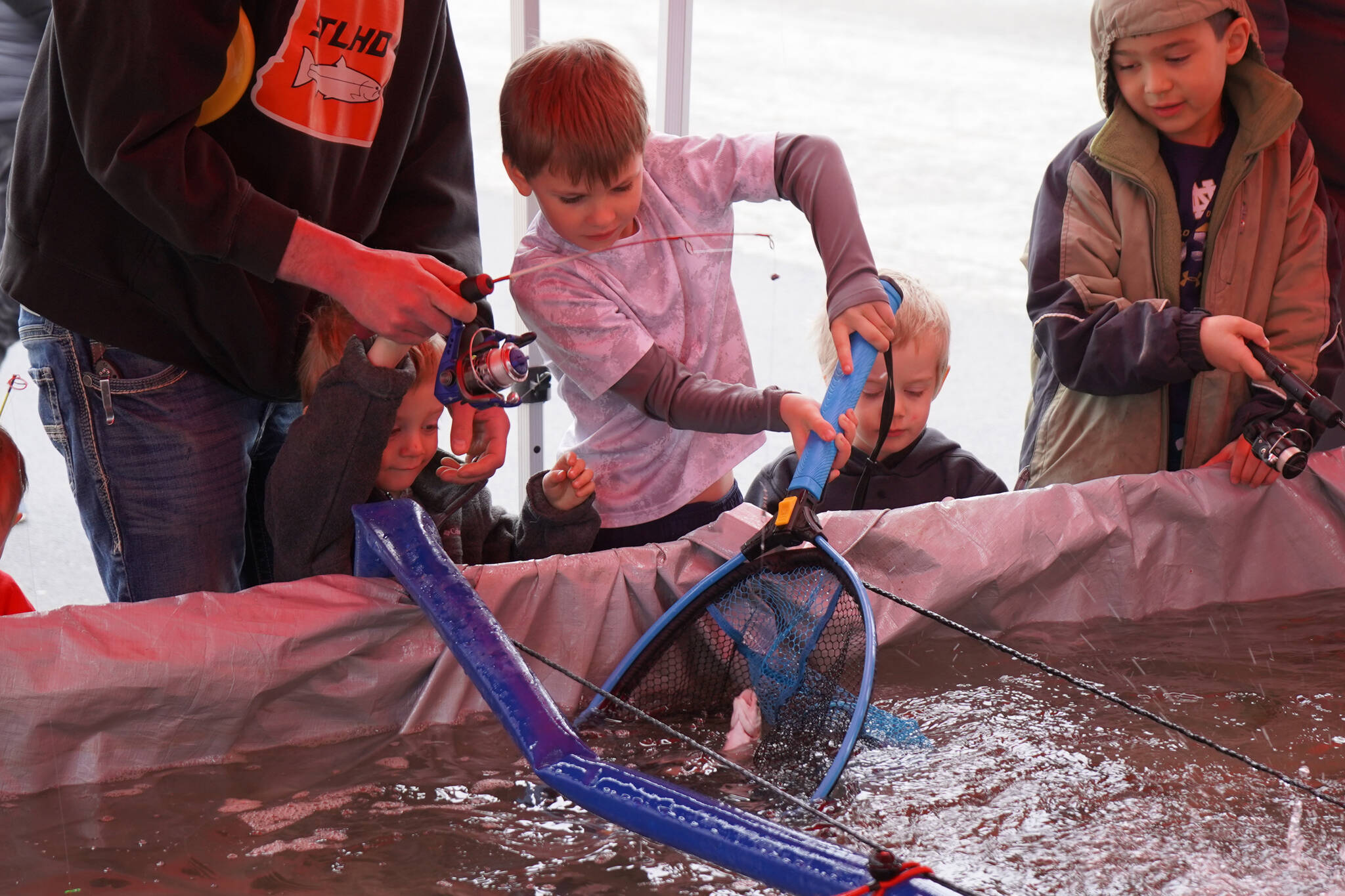 Children work together to land a rainbow trout at the Kenai Peninsula Sport, Rec & Trade Show on Saturday, May 6, 2023, at the Soldotna Regional Sports Complex in Soldotna, Alaska. (Jake Dye/Peninsula Clarion)