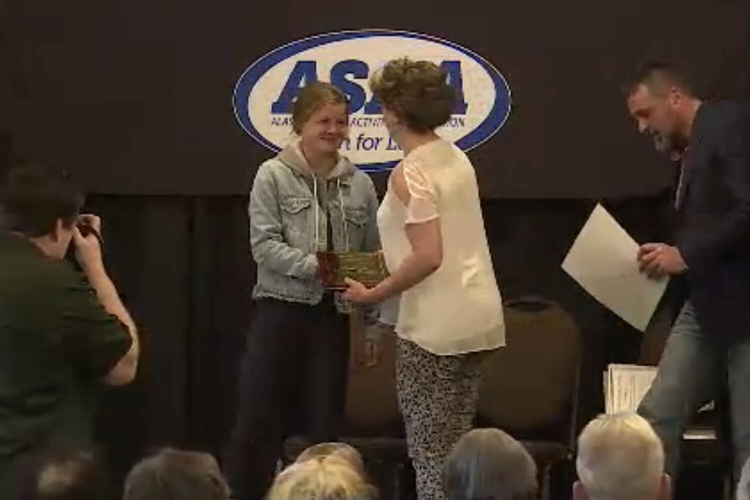Allie Ostrander is presented her award by Stacia Rustad at the Alaska High School Hall of Fame’s Class of 2023 induction ceremony on Sunday, May 7, 2023, at The Lakefront Hotel in Anchorage, Alaska. (Screenshot)