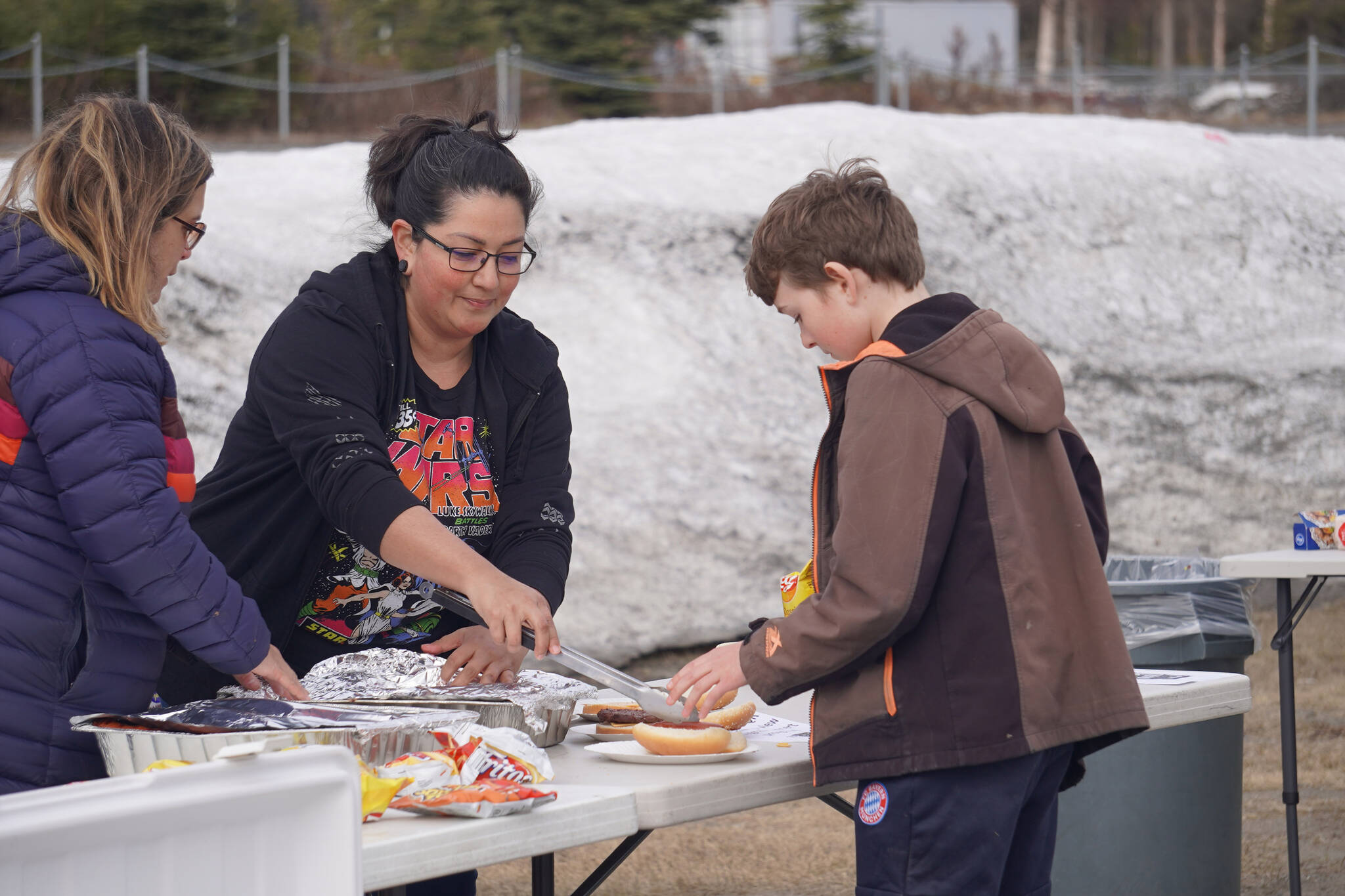 Parent volunteers serve hot dogs and burgers during Pops in the Parking Lot at Kenai Central High School in Kenai, Alaska, on Thursday, May 4, 2023. (Jake Dye/Peninsula Clarion)