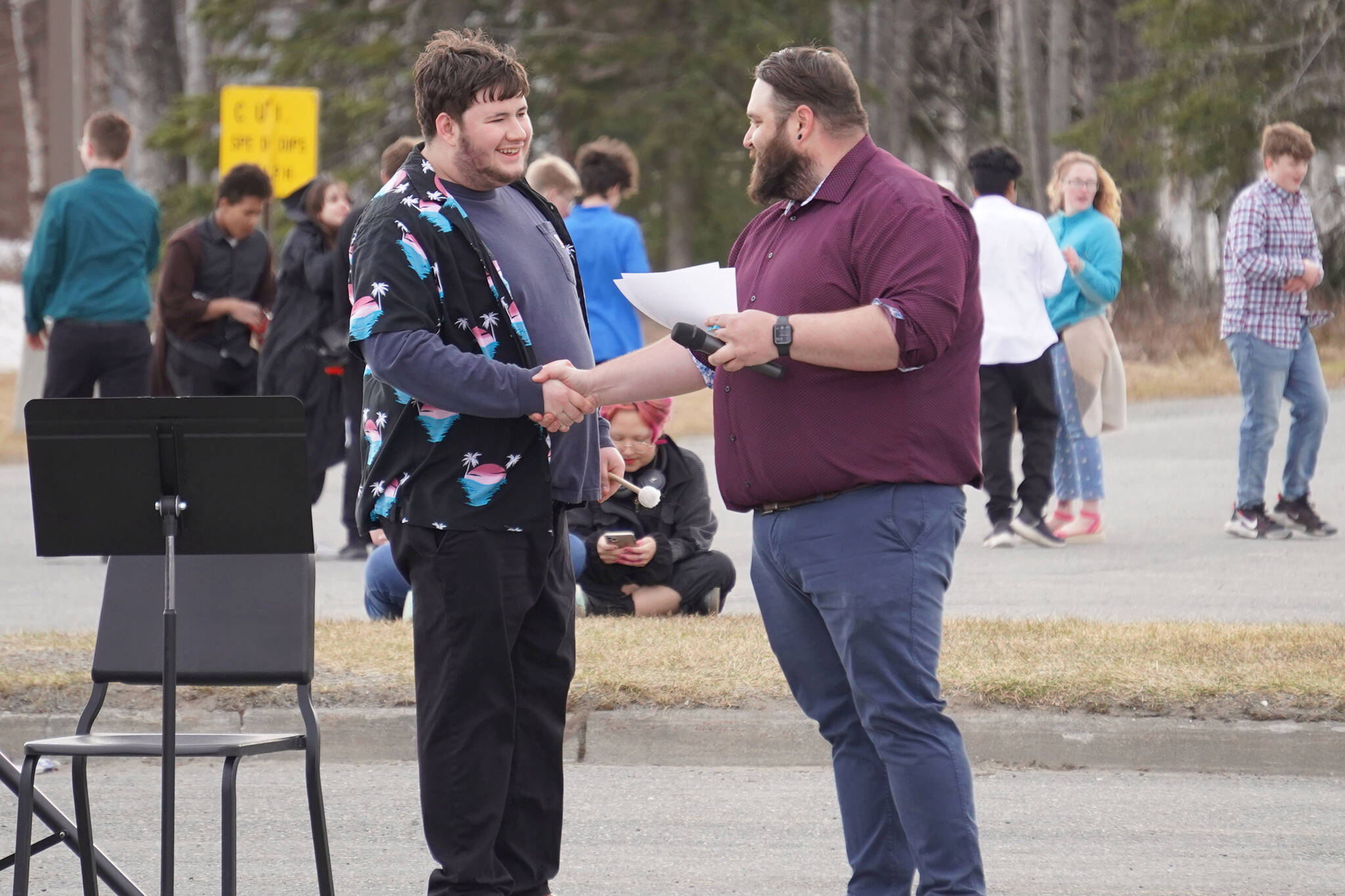 Jake Phillips receives an award and shakes hands with Band Director Christian Stephanos during Pops in the Parking Lot at Kenai Central High School in Kenai, Alaska, on Thursday, May 4, 2023. (Jake Dye/Peninsula Clarion)