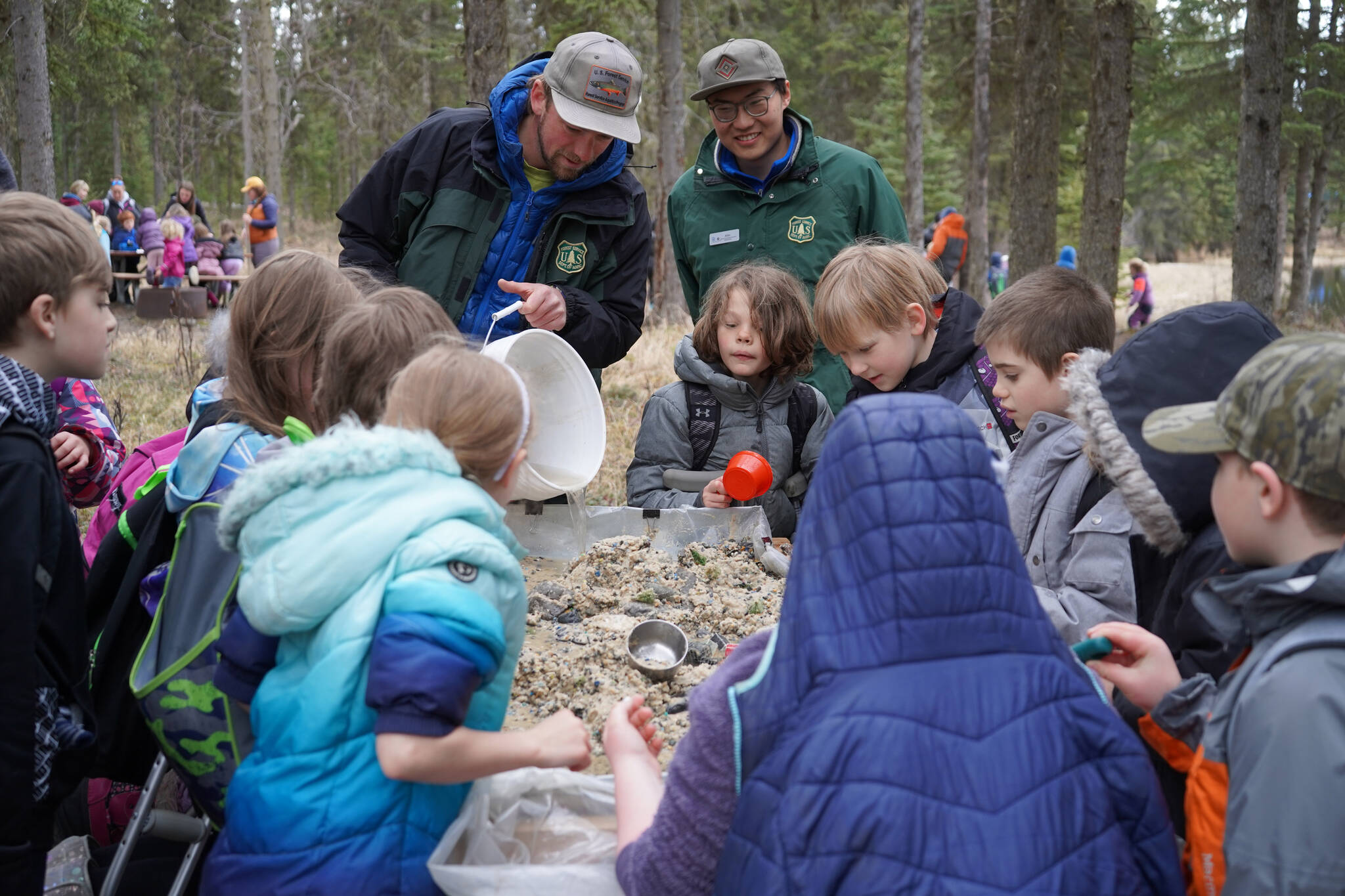 Members of the United States Forest Service demonstrate the flow of a river to elementary students during Salmon Celebration on Wednesday, May 10, 2023, at Johnson Lake in Kasilof, Alaska. (Jake Dye/Peninsula Clarion)