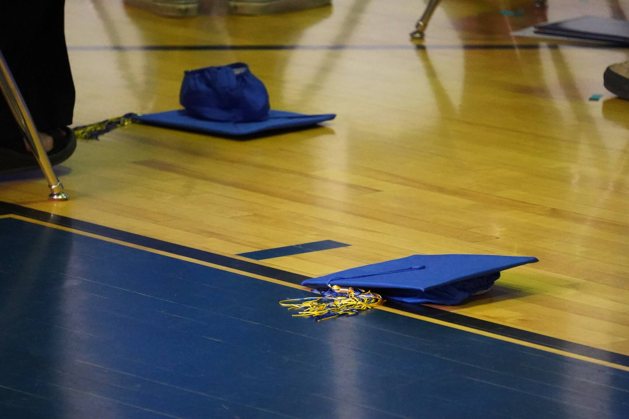 Thrown caps lie on the gymnasium floor during a graduation ceremony on Monday, May 15, 2023, at Kenai Alternative High School in Kenai, Alaska. (Jake Dye/Peninsula Clarion)