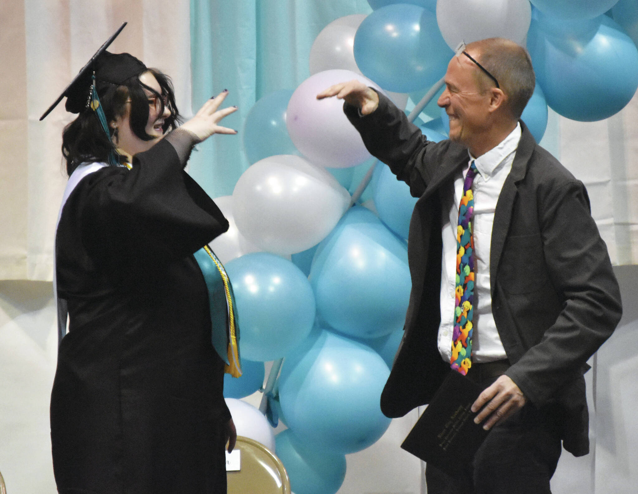 Fiona Wolfe-Jones and teacher Tad DeGray conduct a special handshake before Wolfe-Jones received her diploma at the River City Academy graduation Wednesday. (Photo by Jeff Helminiak/Peninsula Clarion)