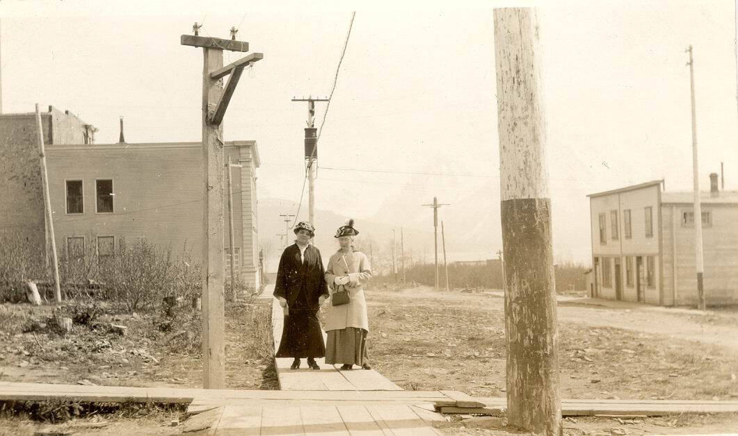 Dr. John Baughman’s wife, Mina (left), poses in this circa 1905-10 photo with Mrs. E.E. Hale on a Seward city sidewalk near the Alaska Central Railroad and Seward’s first school. (Photo #1.628 courtesy of the Seward Community Library Association)