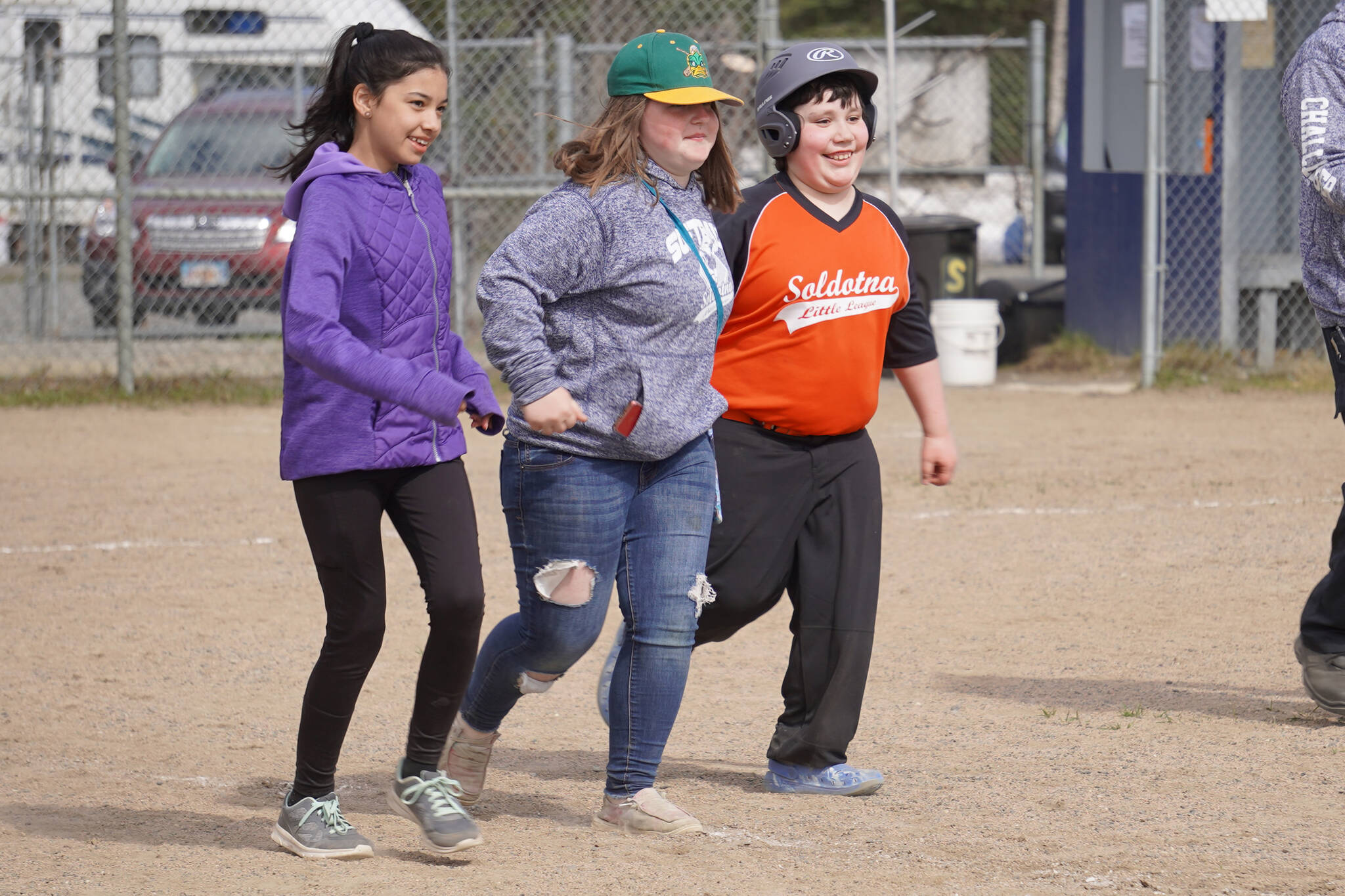 Lila Dockins, MaKenna DesOrmeaux, and Jaeger Romatz run together during Soldotna Little League Challenger Program game at the Little League Fields in Soldotna, Alaska on Saturday, May 20, 2023. (Jake Dye/Peninsula Clarion)