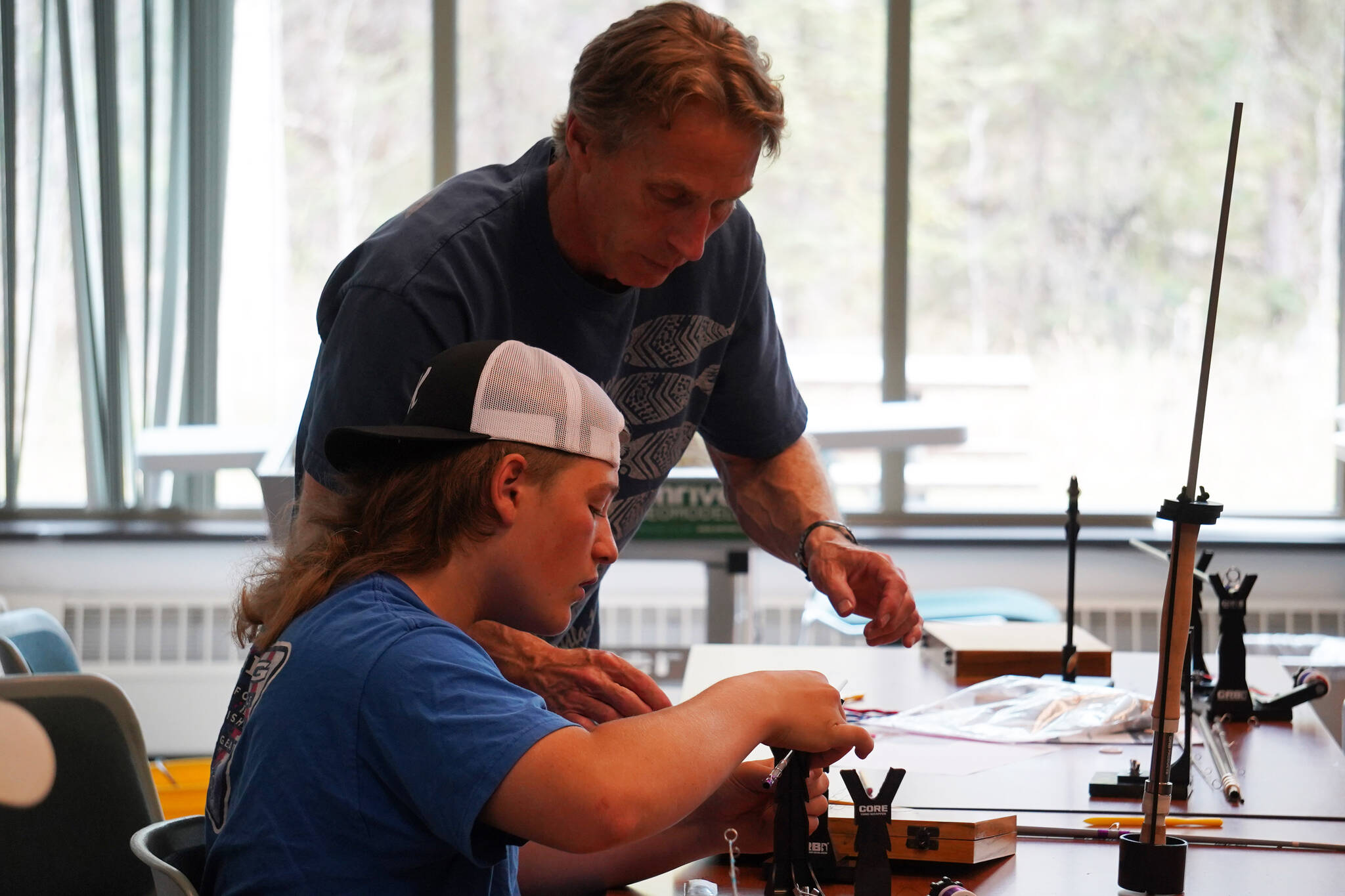 Tony Lewis helps a student with the assembly of a fishing rod during a kids camp put on by Trout Unlimited on Wednesday, May 24, 2023, at the Donald E. Gilman Kenai River Center in Soldotna, Alaska. (Jake Dye/Peninsula Clarion)