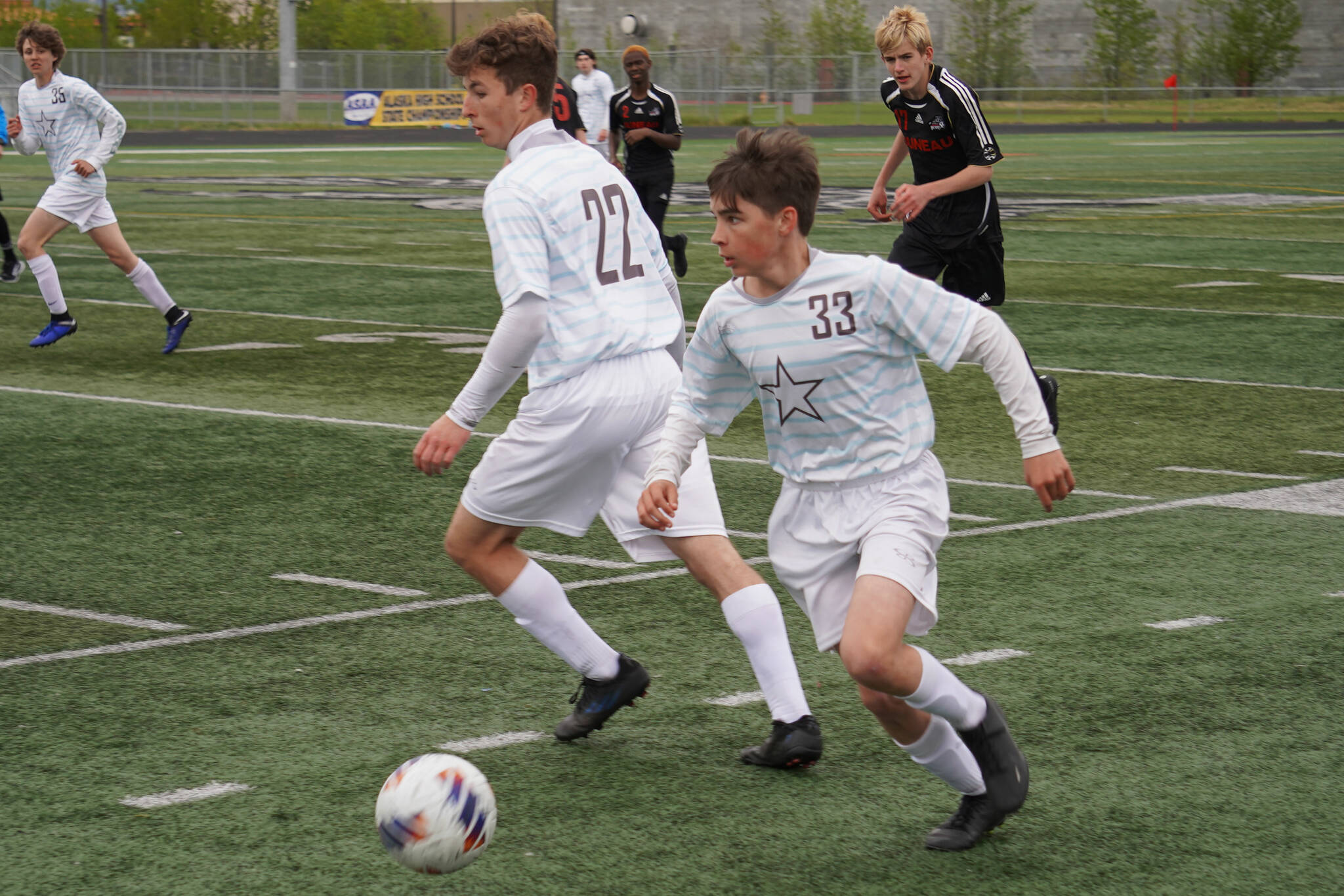 Soldotna’s Lane Hillyer moves with the ball, defended by teammate Zachary Buckbee and pursued by Juneau-Douglas’ Owen Rumsey during the Division II Soccer State Championship on Saturday, May 27, 2023, at West Anchorage High School in Anchorage, Alaska. (Jake Dye/Peninsula Clarion)